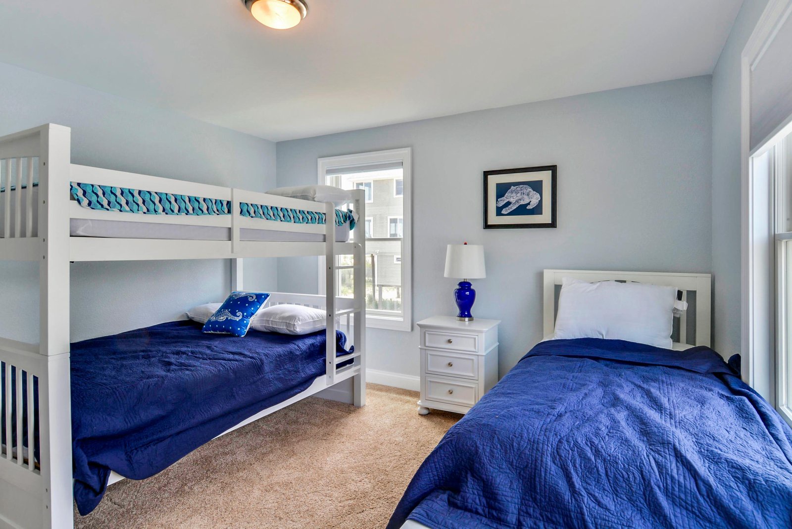 Settle in for the night in this bright coastal bedroom with plush beds and soothing blue accents designed for your comfort and rest.