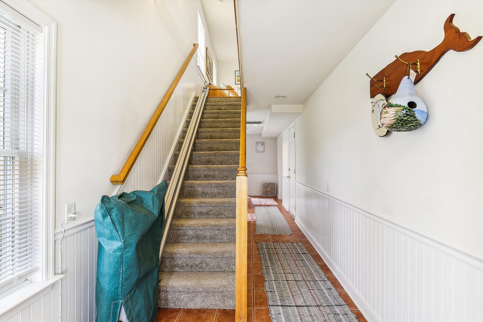 A bright hallway leads you upstairs, showcasing coastal charm with unique nautical decor and warm wood accents welcoming you to your upper-level retreat.