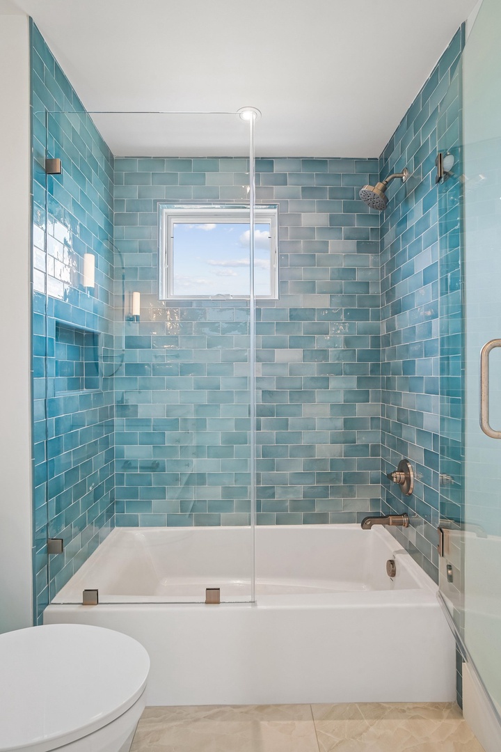 Refresh and rejuvenate in your private bathroom adorned with calming sea-glass tiles, a soaking tub, and rainfall shower. The bright coastal palette and gleaming fixtures create a spa-like escape for unwinding after a day of adventure.