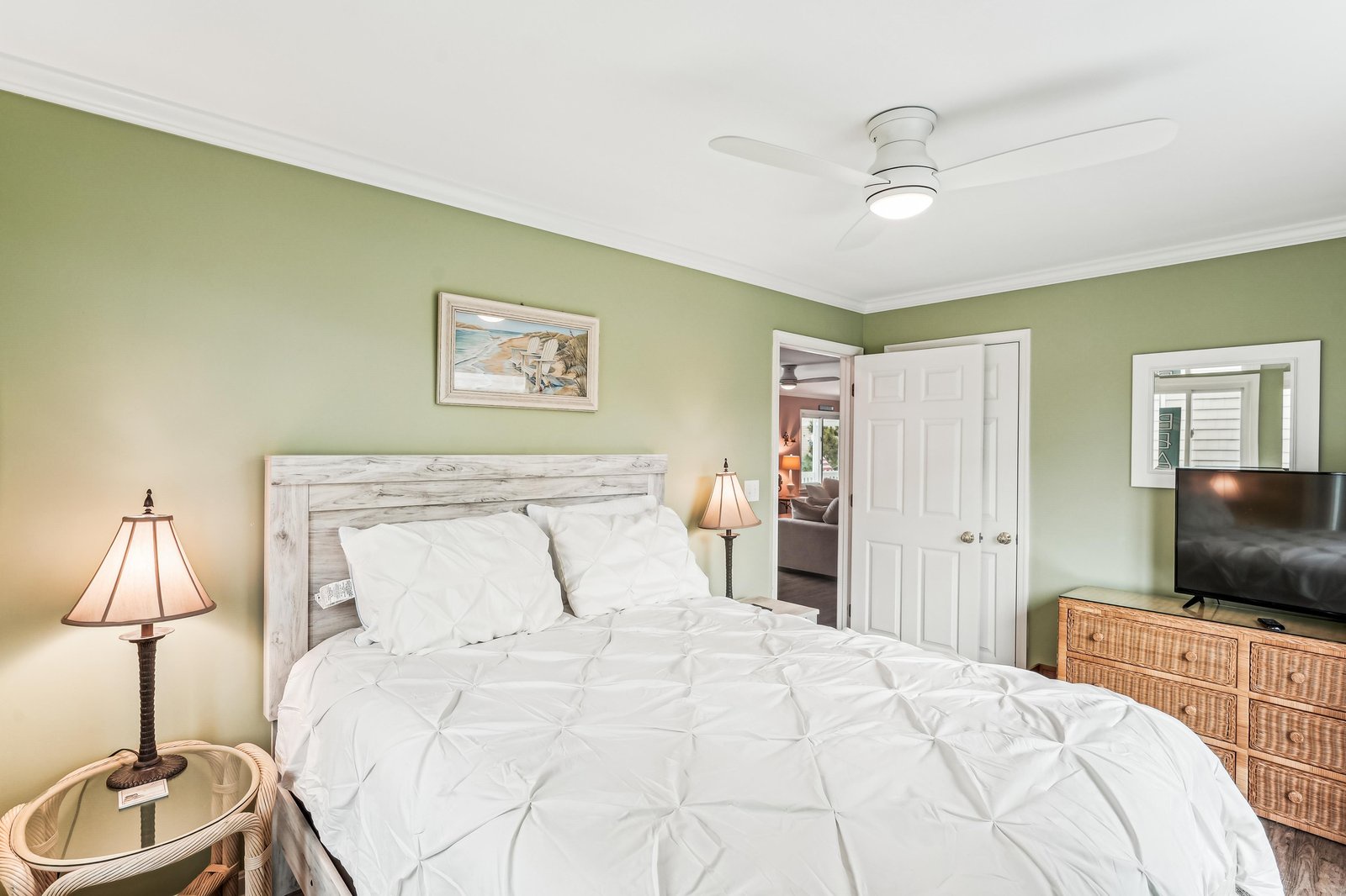 Drift off to sleep in your tranquil retreat, where soft green walls and crisp white linens invite you to unwind beneath a gentle ceiling fan after a long day of exploring.