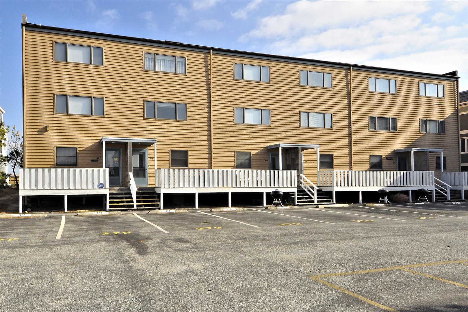 A multi-unit vacation rental building with warm wood siding, private decks, and convenient parking, located in a peaceful coastal area.