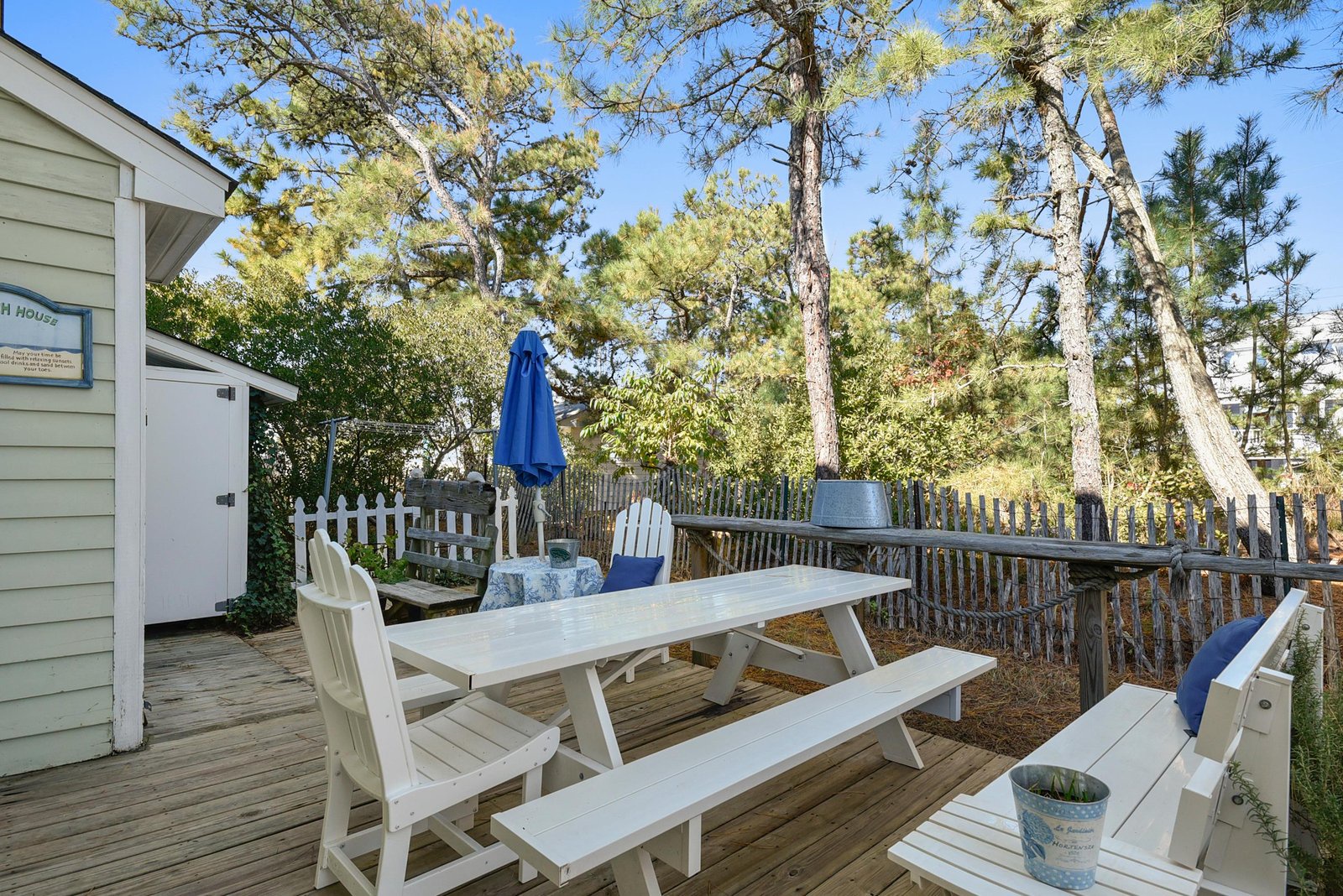 Step outside to your private deck, where tall pines frame a bright blue sky and your morning coffee table awaits—perfect for meals outdoors or just relaxing in the fresh air.