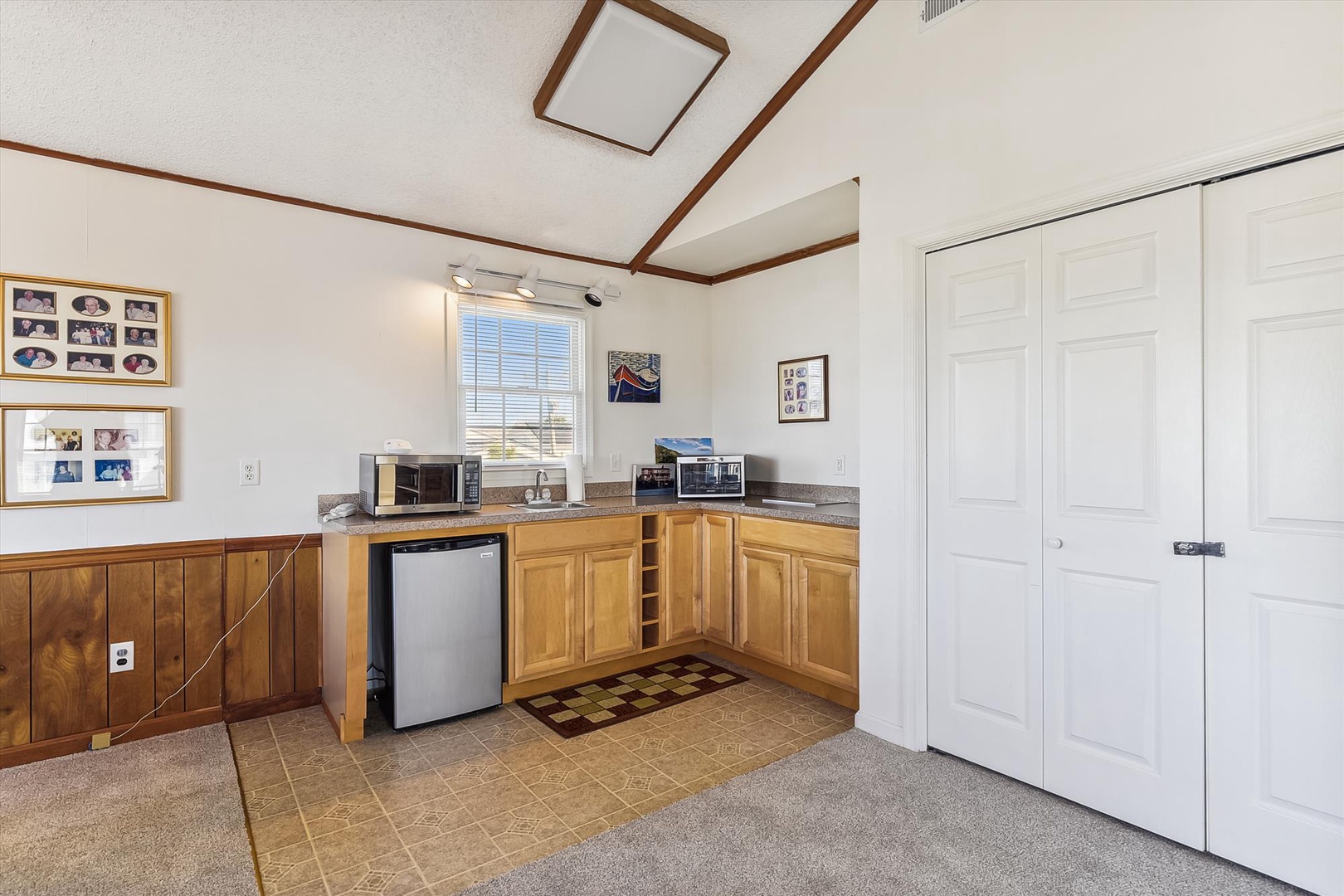 Your private kitchenette awaits, fully equipped with a mini fridge, microwave, coffee maker, and warm wood cabinetry. Natural light pours through the window as you prepare snacks or morning coffee in this cozy, self-sufficient space.