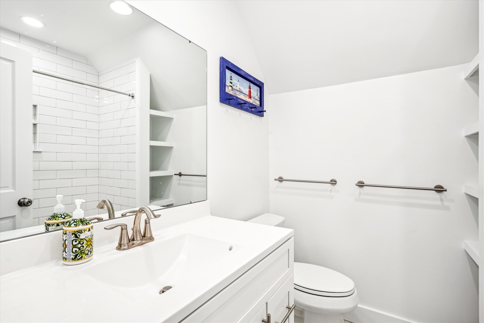 Step into a pristine bathroom with crisp white finishes, stylish subway tile, and thoughtful touches like built-in shelving for your essentials—bright, clean, and ready for your stay.
