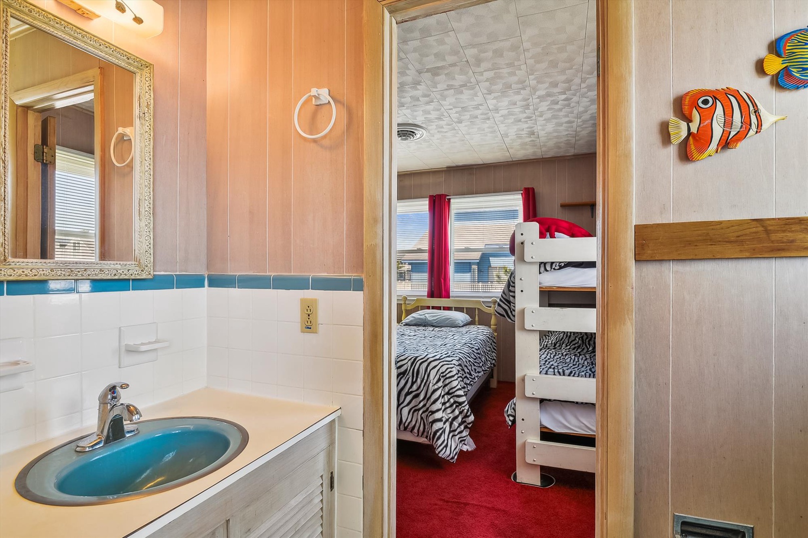 Playful fish art adds whimsy to your bright bathroom, adjacent to a cozy bedroom with twin and bunk bed setups perfect for families.
