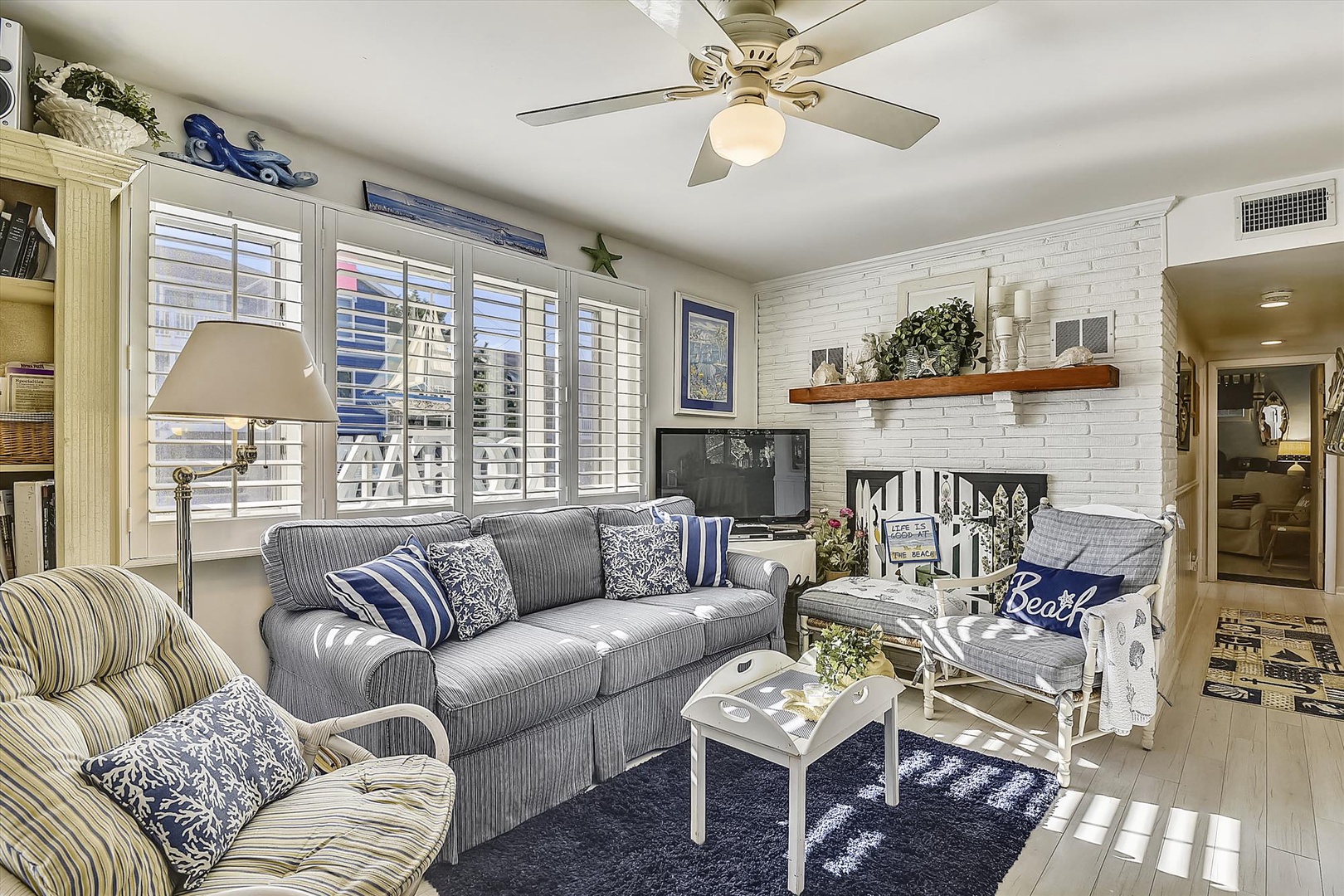 Relax in your bright, nautical-themed living space with cozy seating, a gentle ceiling fan, and coastal charm in every detail—perfect for unwinding after a day of adventures.