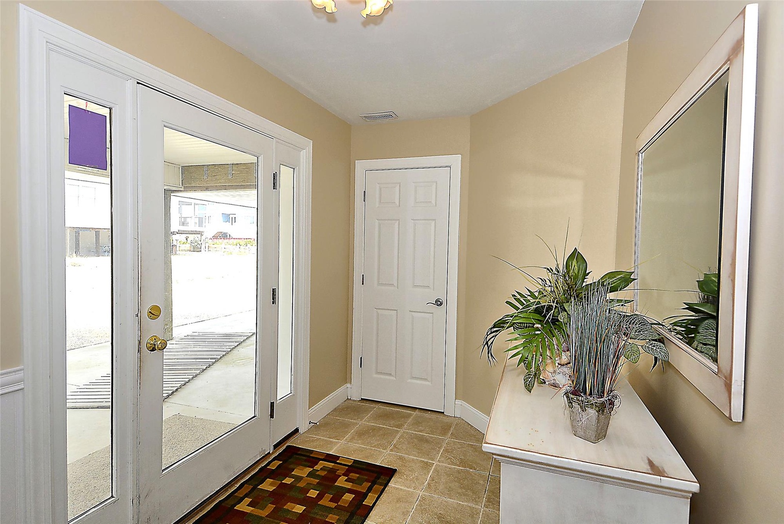 A welcoming entryway with bright natural light and elegant finishes greets you at the door. A stylish mirror and fresh greenery create an inviting arrival space for your stay.
