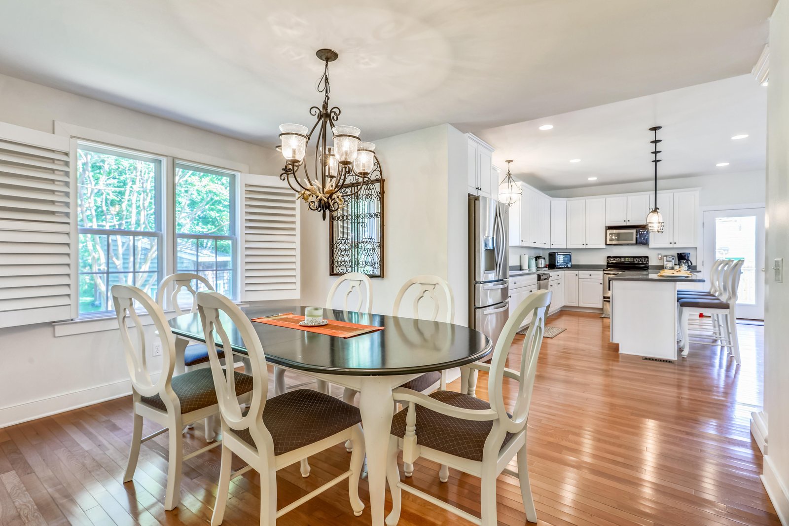 Gather around the elegant dining table for meals with loved ones, bathed in natural light from the large windows overlooking lush greenery. The open layout flows seamlessly into the bright, fully equipped kitchen, making hosting effortless.
