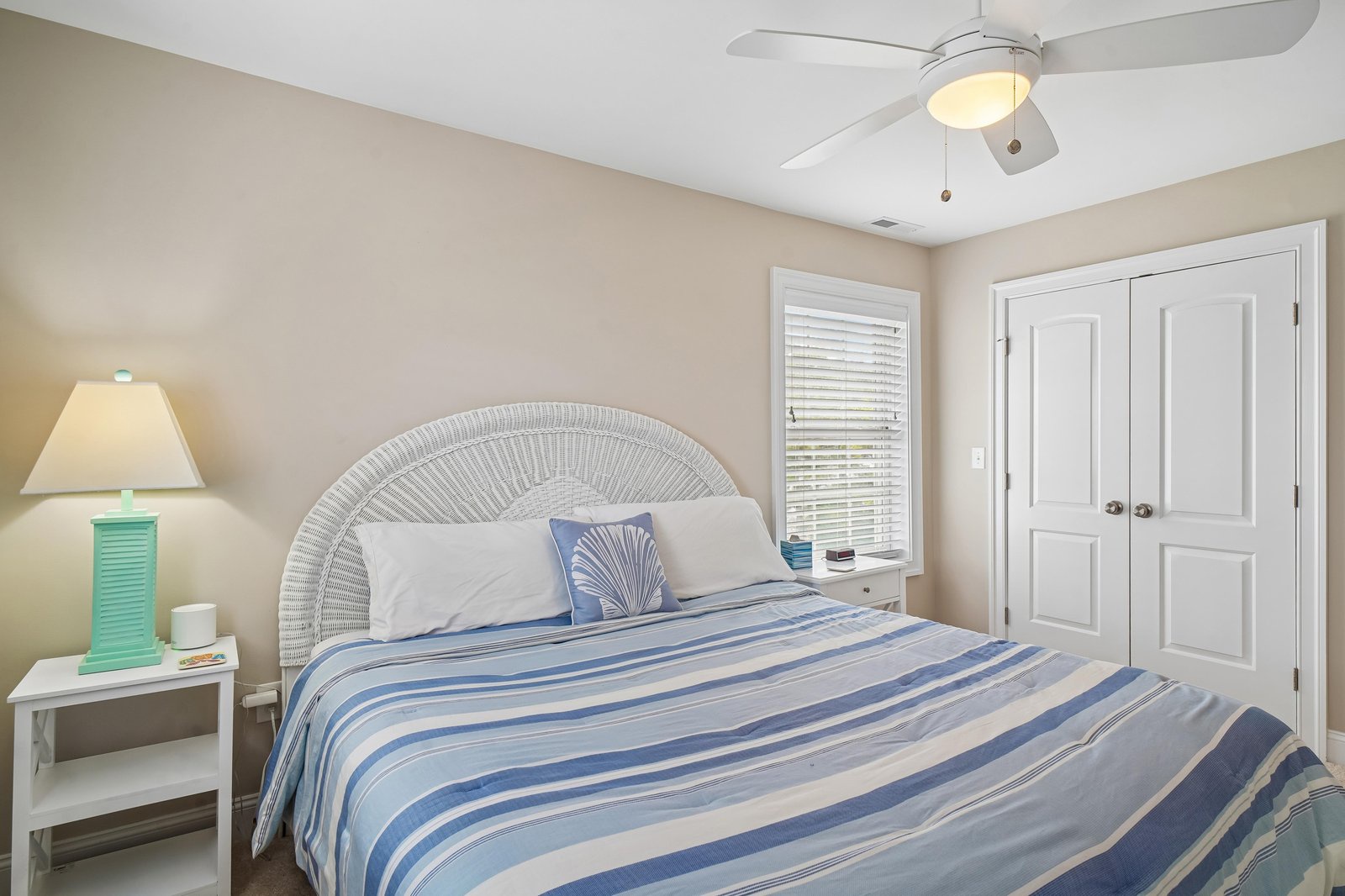 Rest easy in this serene bedroom, where soft coastal tones and a comfortable bed invite you to unwind after a day of adventure. The ceiling fan keeps you cool as gentle light filters through the window.