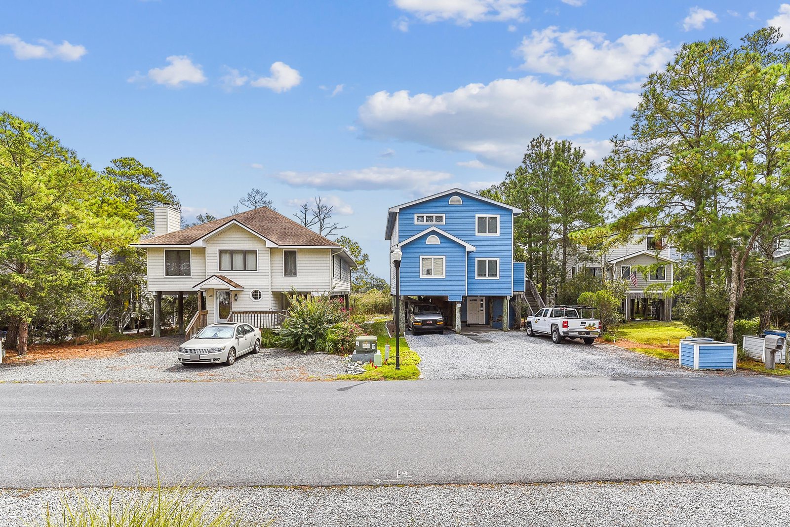 Bright blue rental property nestled in a peaceful wooded neighborhood with convenient parking and spring foliage all around.