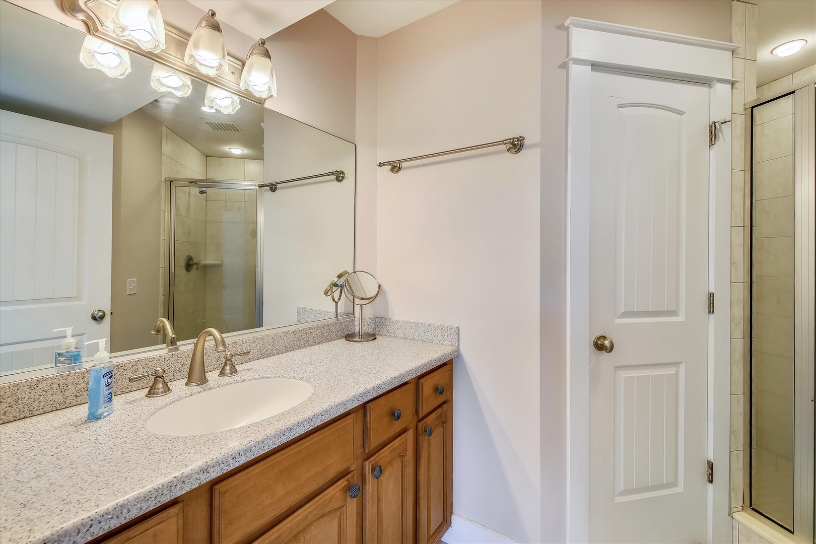 Your private bathroom features a spacious vanity with granite countertops, elegant vanity lighting, and a glass-enclosed shower for a refreshing start to your day.