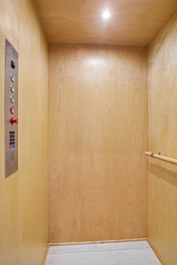 Light wood-paneled elevator interior with modern control panel and handrail for your comfort and convenience.