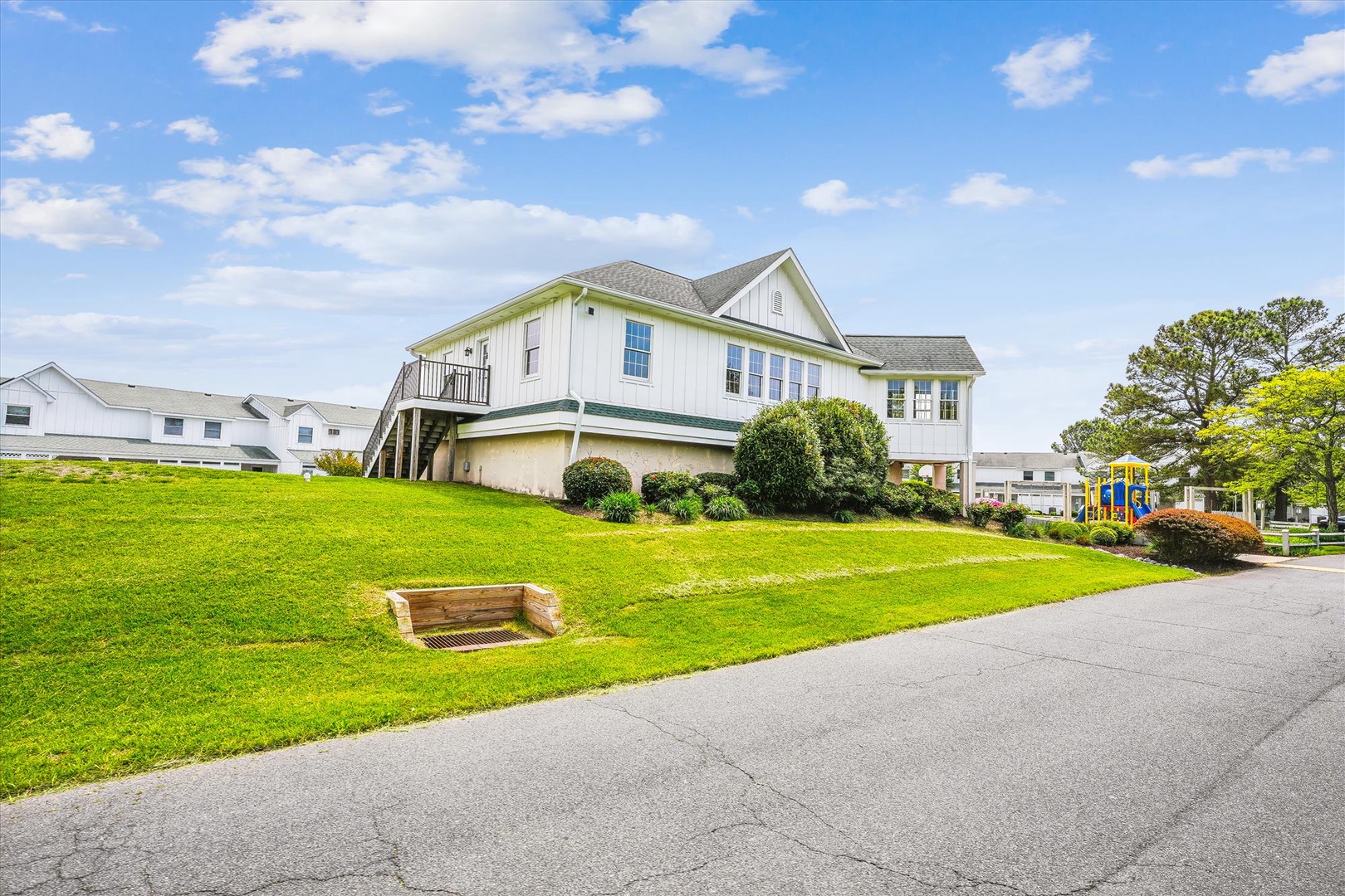 This elevated coastal property offers expansive lawns and mature landscaping in a family-friendly neighborhood, with a children's playground visible nearby.
