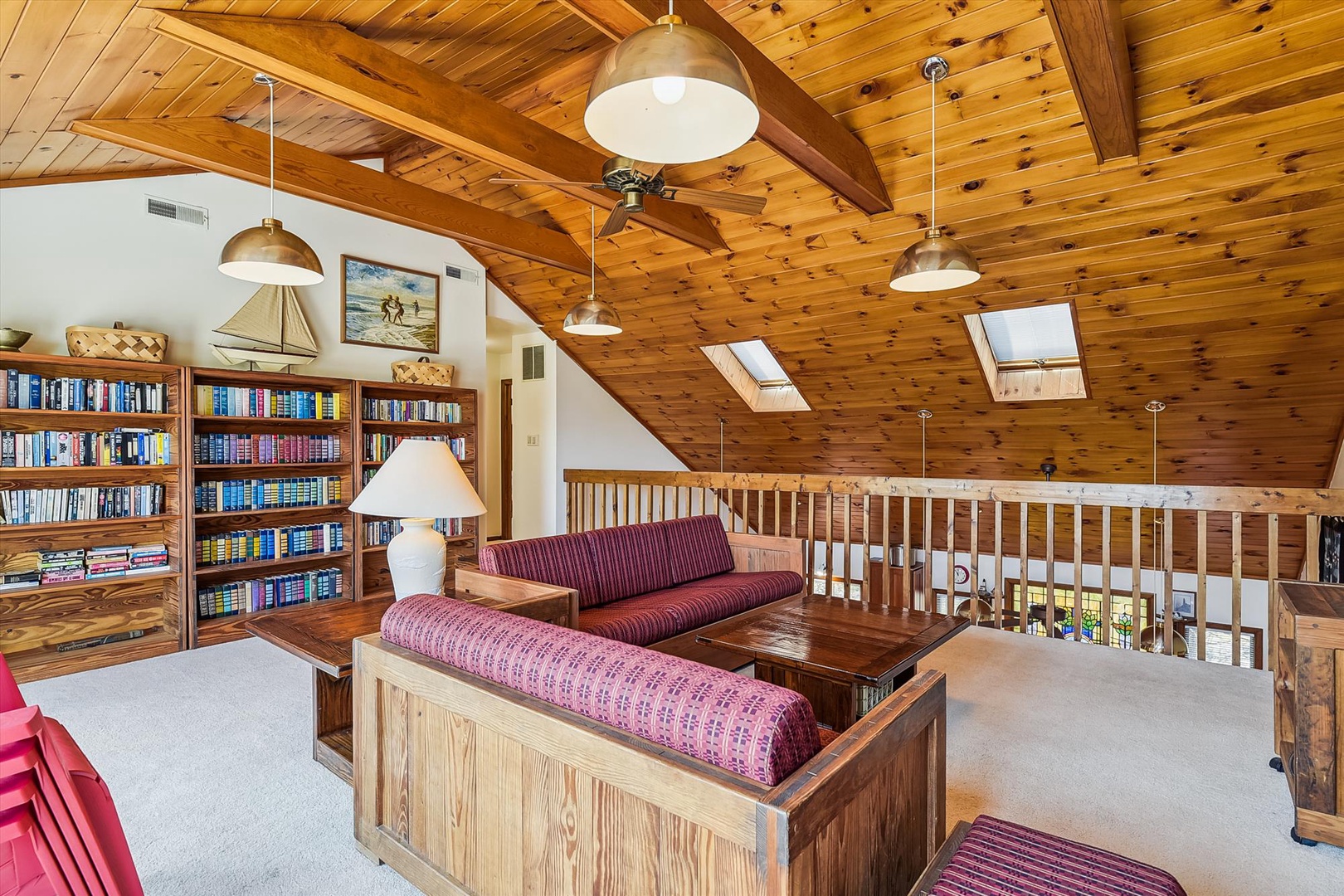 Curl up with a favorite book in this inviting loft, where warm wood beams frame your reading nook and natural light pours through skylights above.