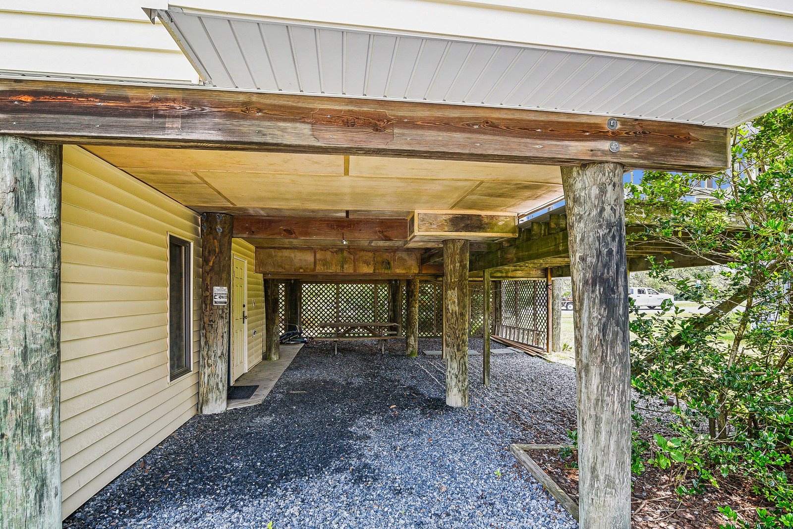 A covered parking area featuring rustic wooden beams and gravel flooring, providing shelter for your vehicle while connecting you to the peaceful natural surroundings.