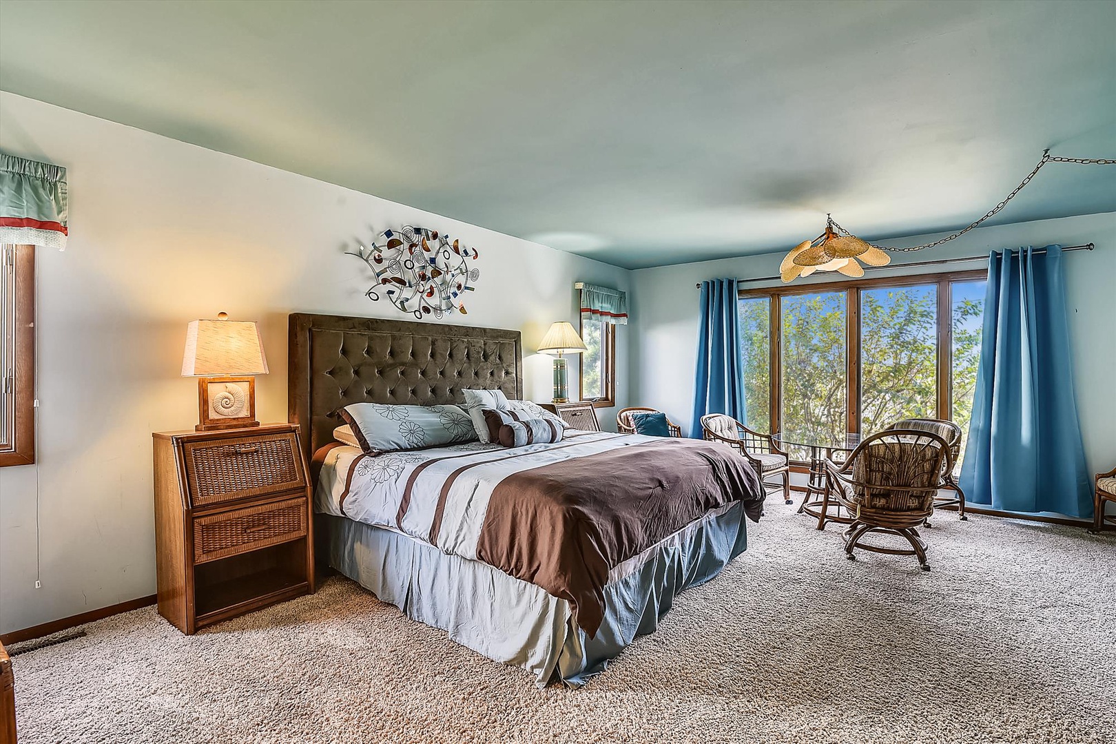 Your peaceful retreat awaits in this spacious bedroom, where natural light floods through glass doors and soft teal tones create a calming atmosphere for your restful getaway.