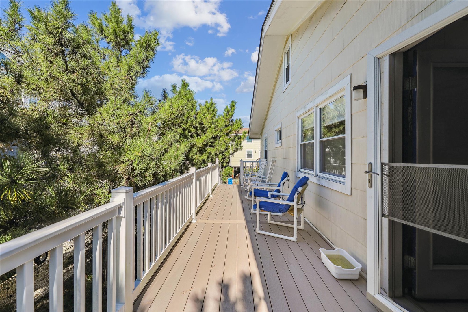 Sip your morning coffee on this sunny deck overlooking tall pines and blue skies, where relaxation awaits in comfortable lounge chairs.