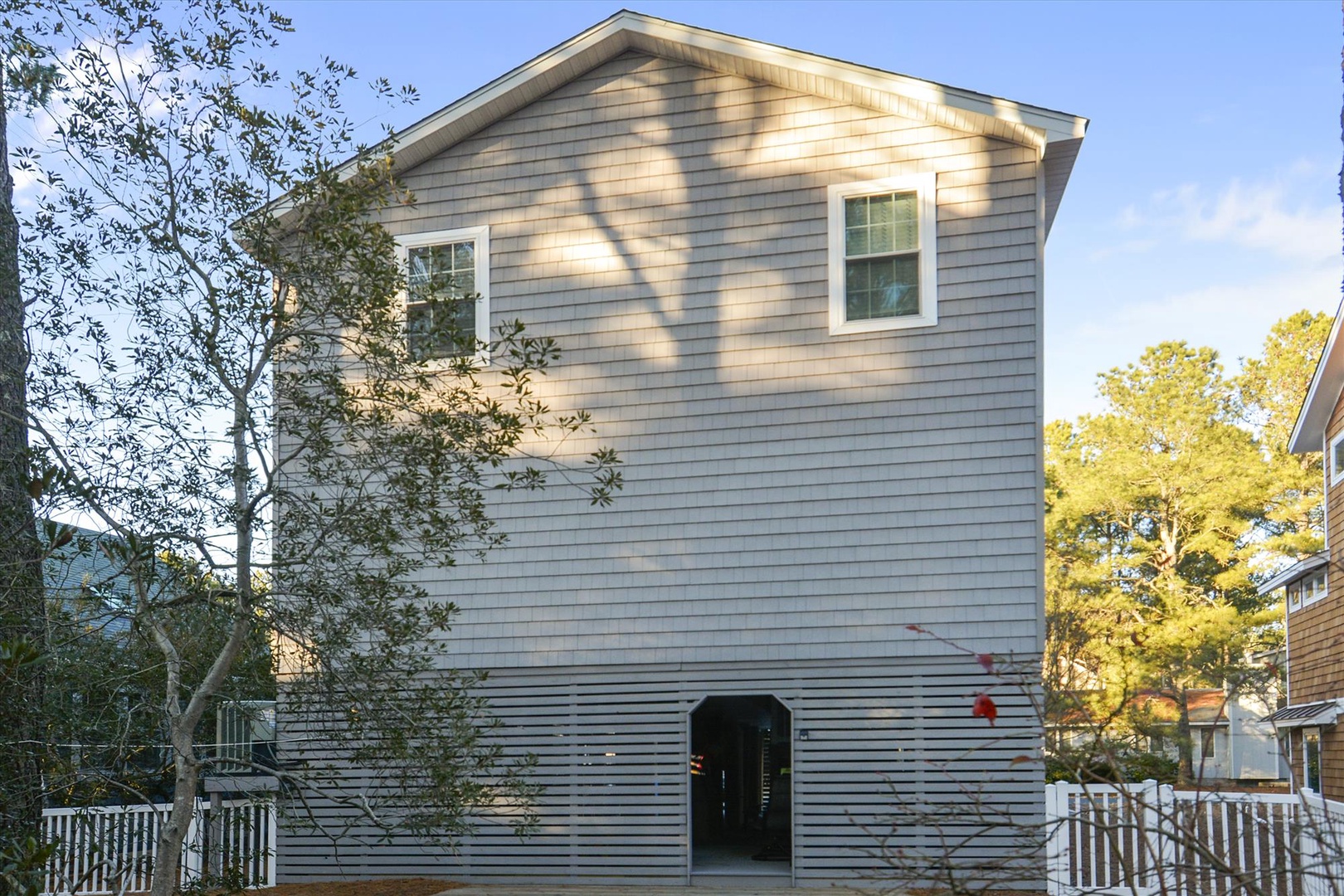 A charming two-story vacation home with natural wood siding nestled in a tree-lined neighborhood, offering a peaceful retreat during your stay.
