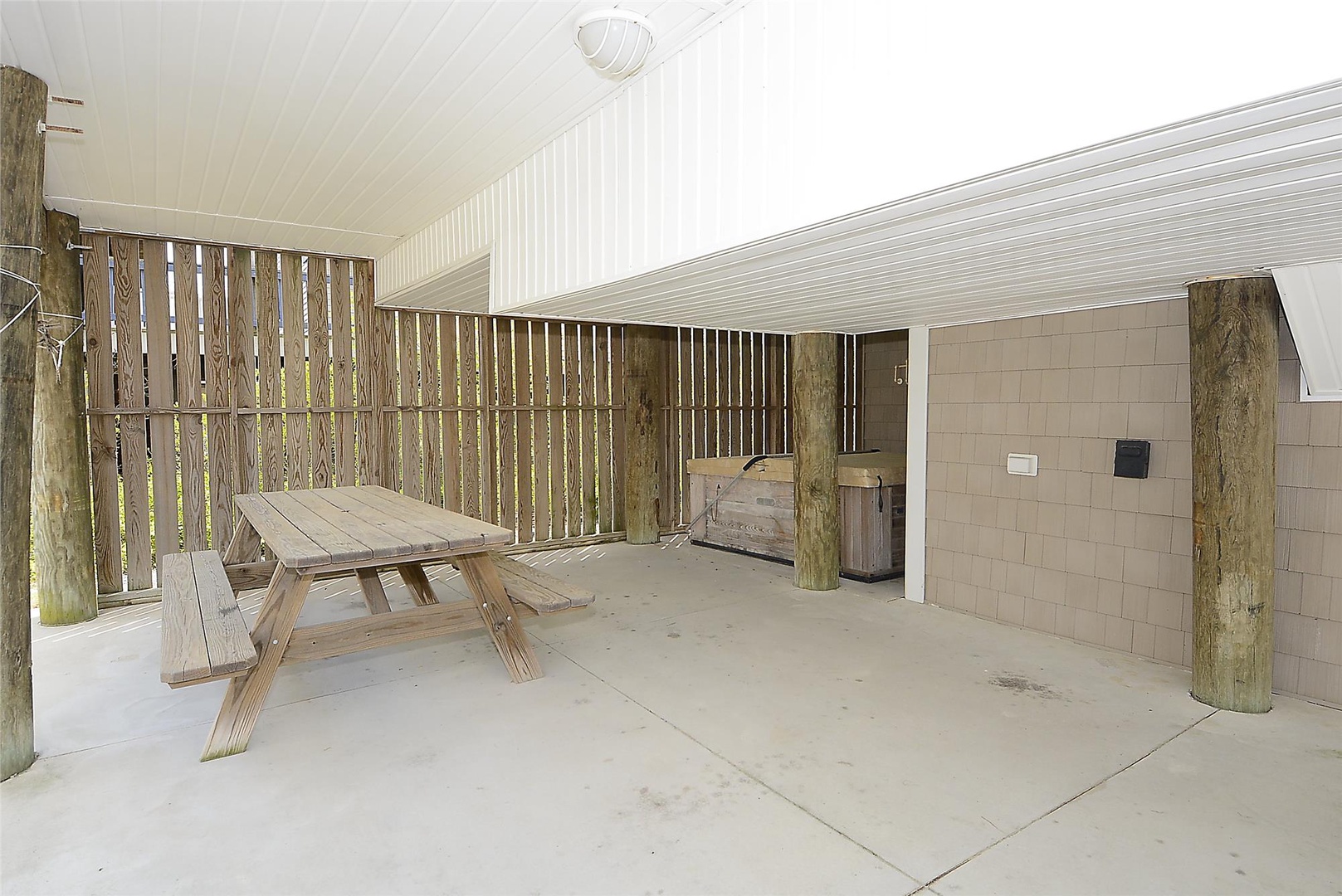 A covered outdoor patio features a rustic wooden picnic table, perfect for morning coffee or evening meals. Natural wood accents and privacy fencing create your own secluded retreat space.