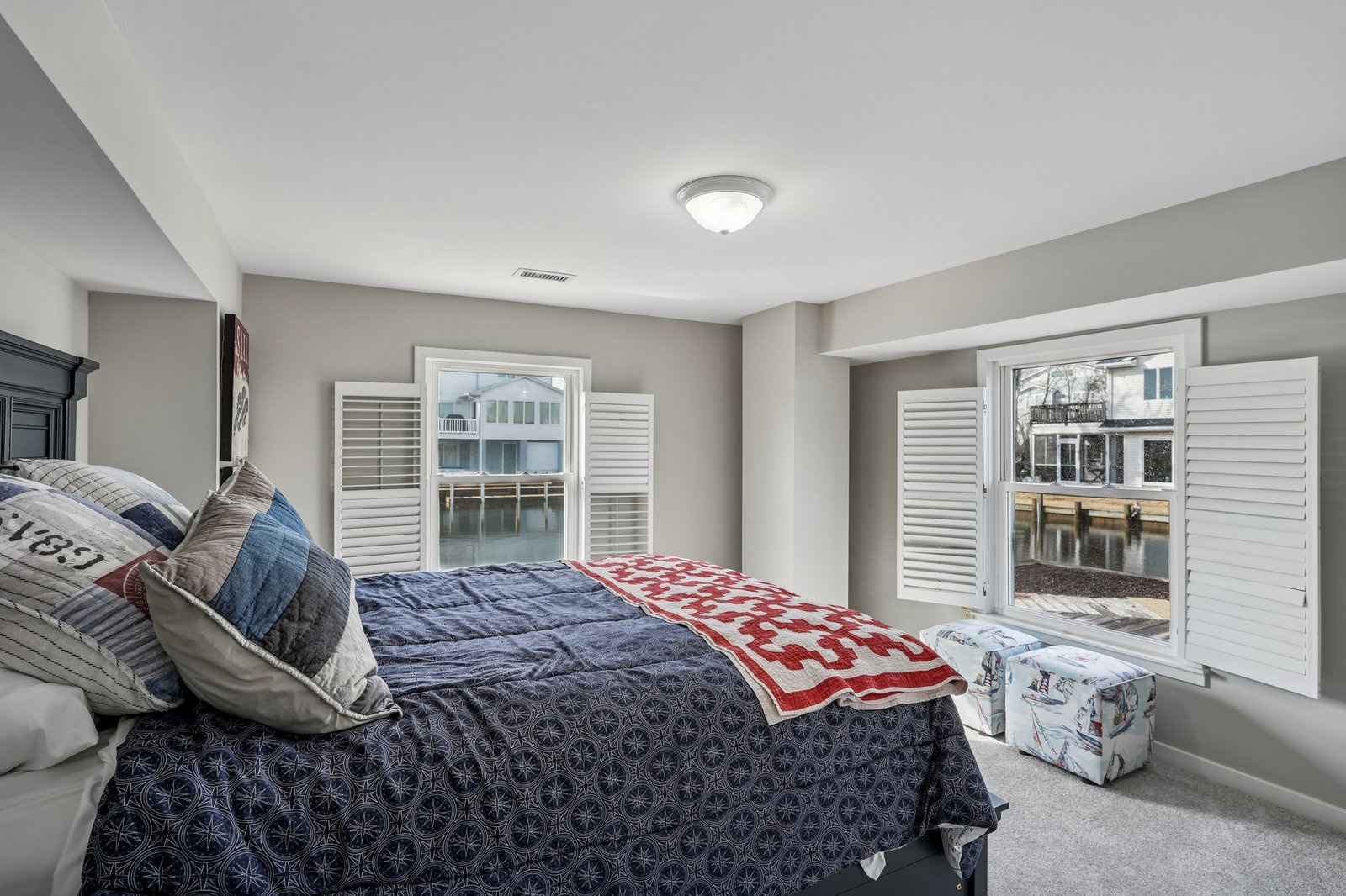 Wake up to serene waterfront views from your cozy bedroom, where nautical-inspired linens and bright windows create the perfect coastal retreat.