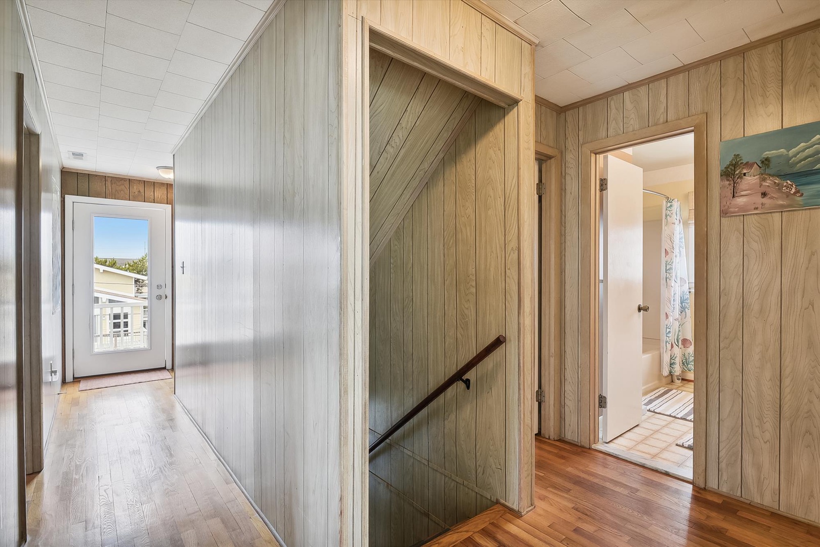 Step into a bright, wood-paneled entryway with charming details and easy access to your cozy bedroom, where warmth and coastal character greet you at the door.