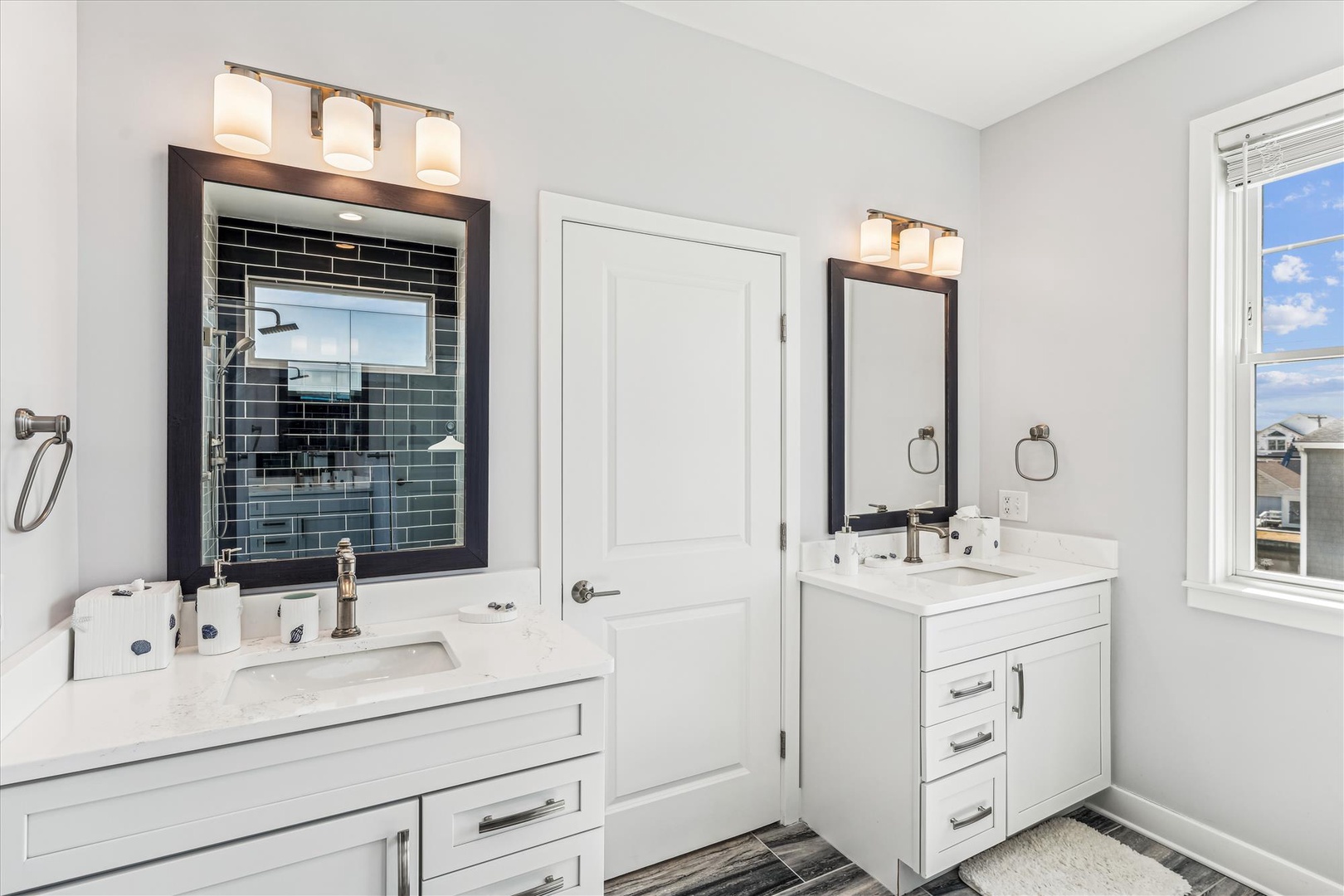 Freshen up in this elegant dual-vanity bathroom featuring pristine white countertops, stylish tile details, and abundant natural light streaming through your private window.