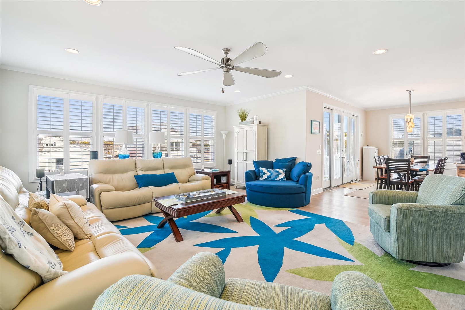 Your spacious open-plan living area welcomes you with coastal-chic décor, comfortable seating, and bright natural light streaming through plantation shutters.