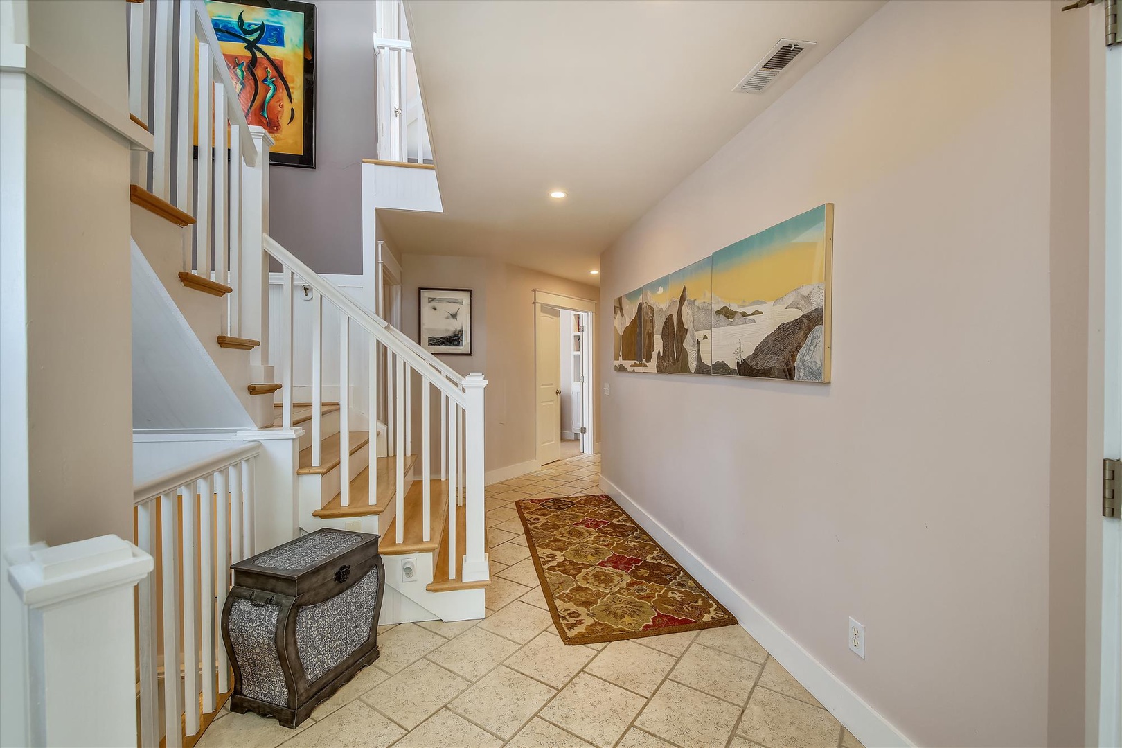 Step into your welcoming entrance, where warm tile floors and carefully chosen artwork invite you to settle in. The bright hallway and elegant staircase guide you upward to your private retreat above.