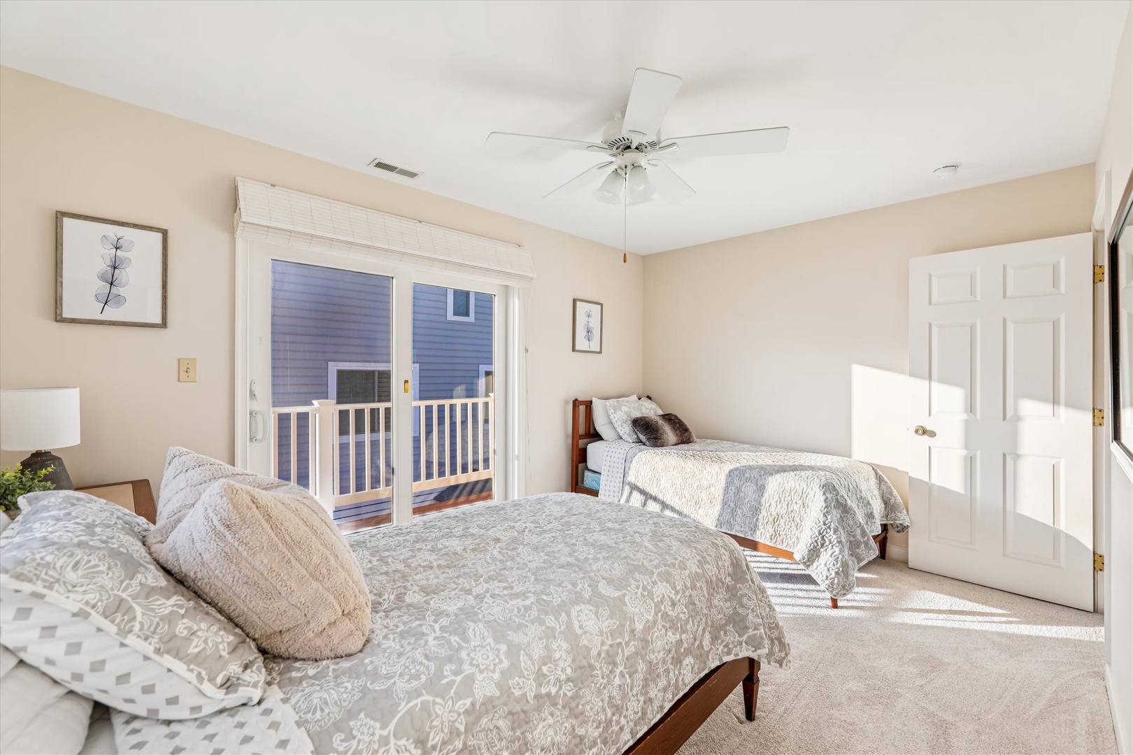 Wake up in this peaceful twin-bed room with natural light streaming through sliding doors. You'll love the coastal charm and gentle ceiling fan breeze.