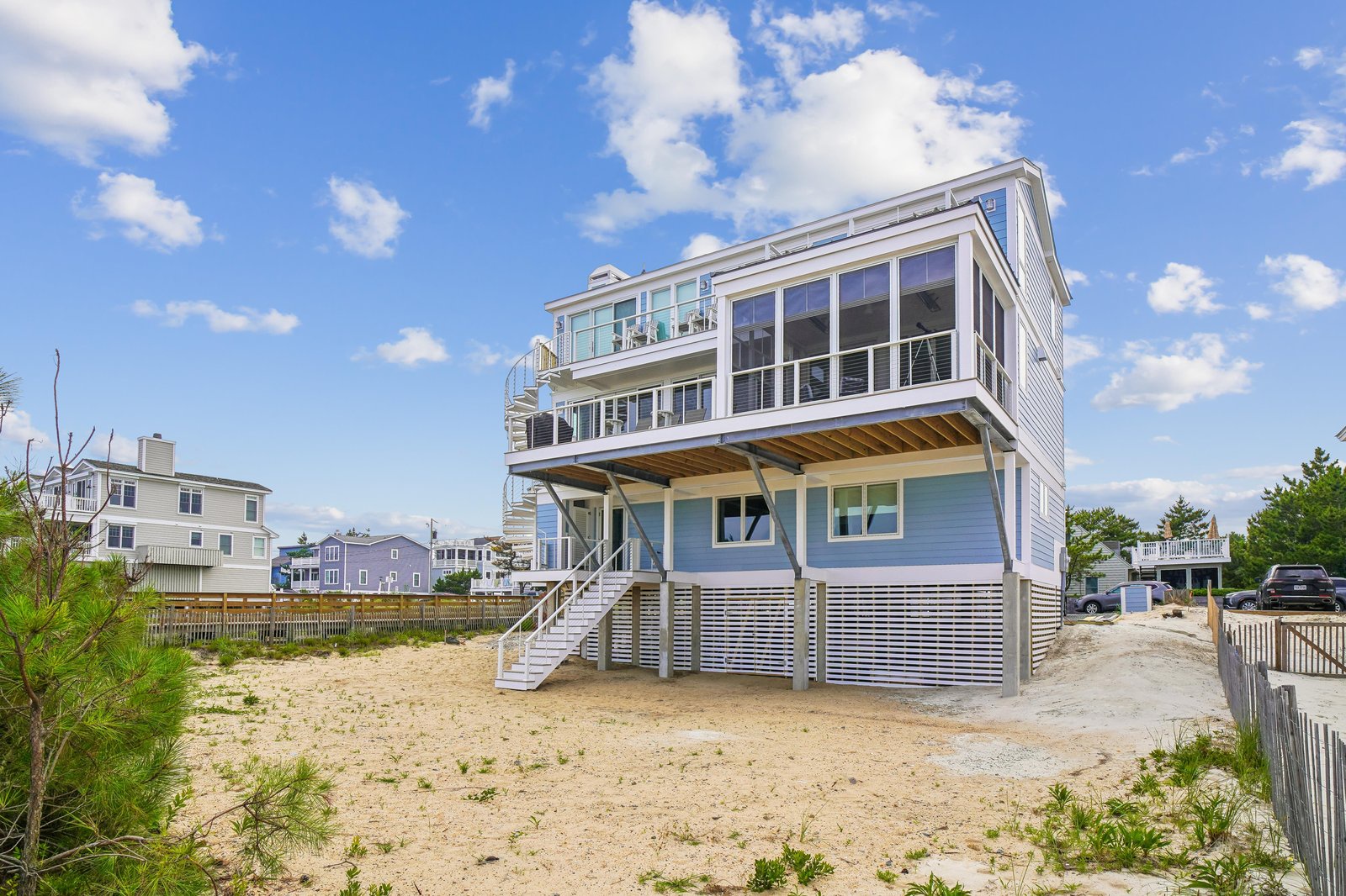 A stunning three-level beach house stands just steps from the sand, featuring expansive balconies and floor-to-ceiling windows that frame endless ocean panoramas.