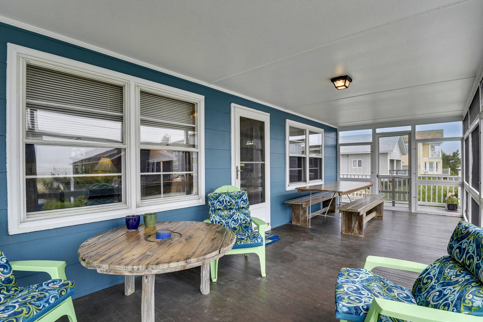 Your covered porch invites you to unwind with cozy seating and a long dining table, perfect for morning coffee or sunset gatherings by the shore.