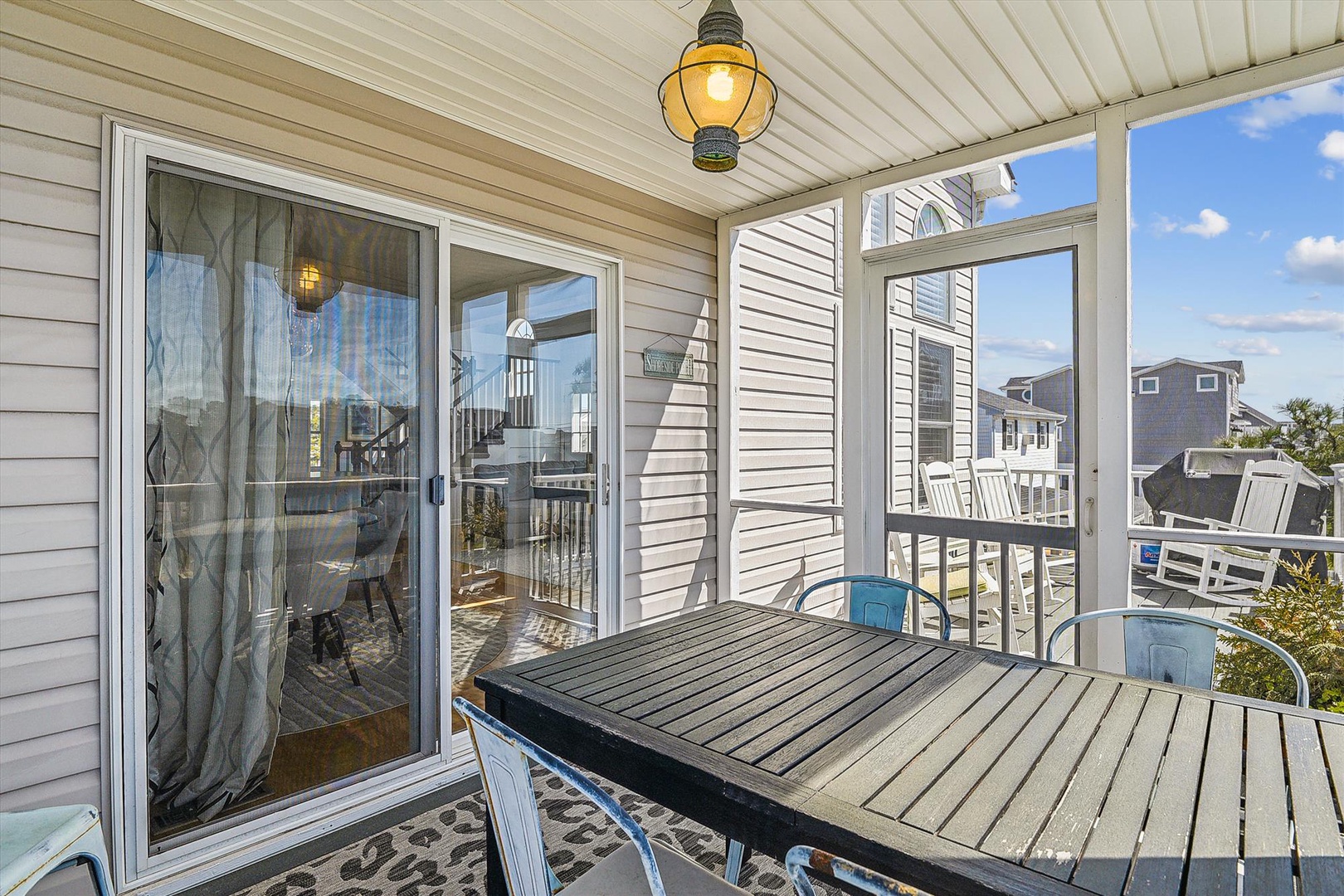 Your private screened porch offers peaceful mornings with coffee under a charming lantern, overlooking the neighborhood—an ideal spot to unwind and plan your day.