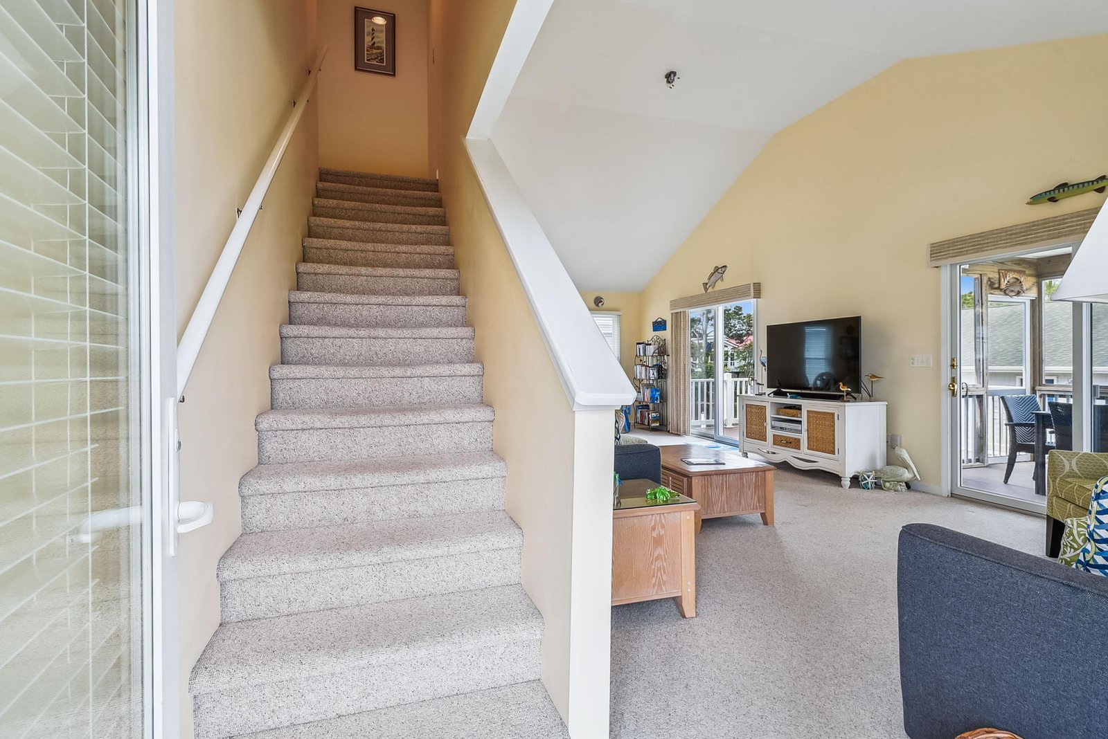 Bright, open living area with vaulted ceilings and natural light streaming through the balcony doors—your perfect retreat after a day at the beach.