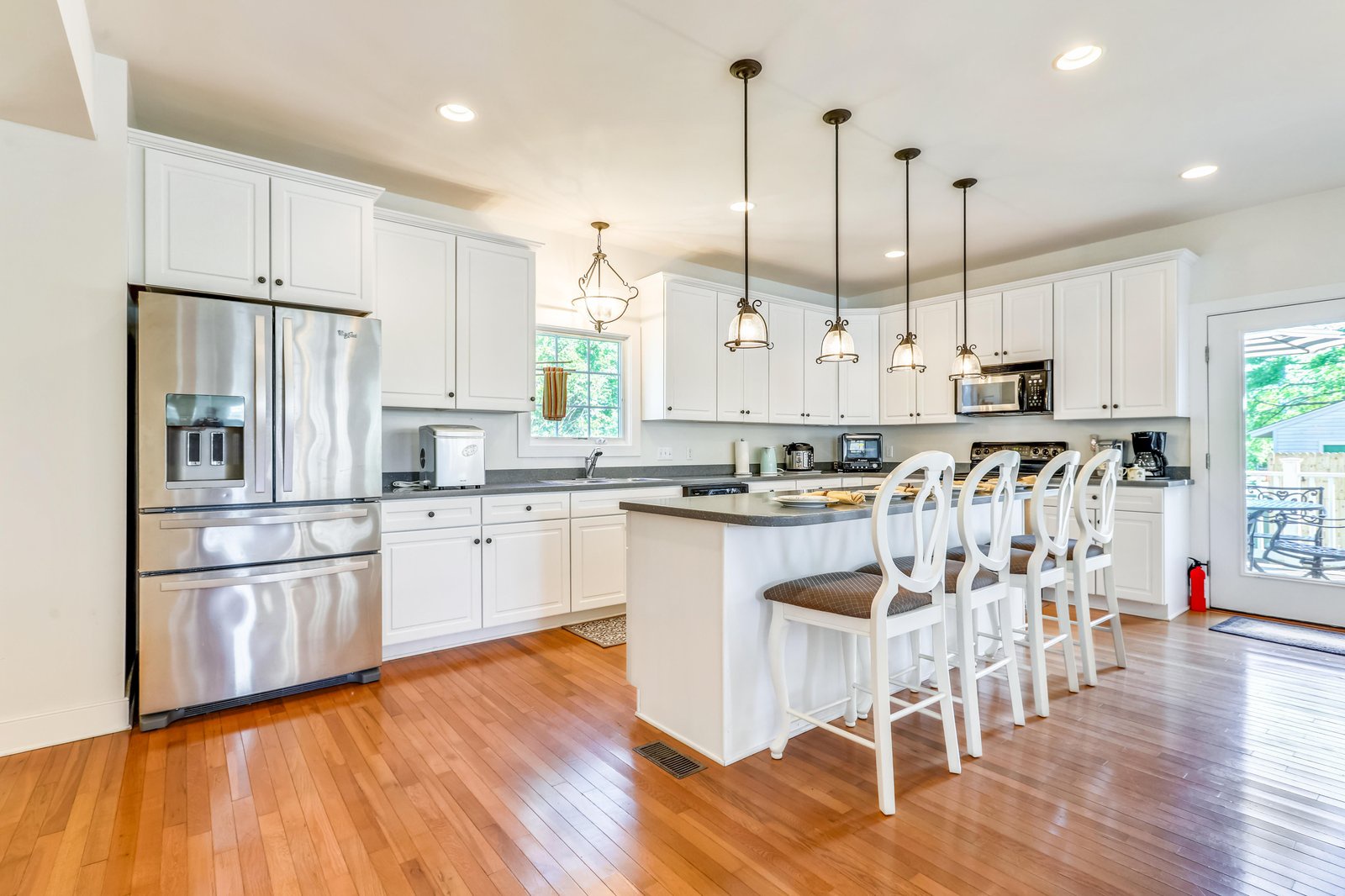 Picture yourself preparing morning coffee in this bright, spacious kitchen with gleaming countertops and warm hardwood underfoot. The island invites you to gather with family over breakfast while natural light streams in through the windows.