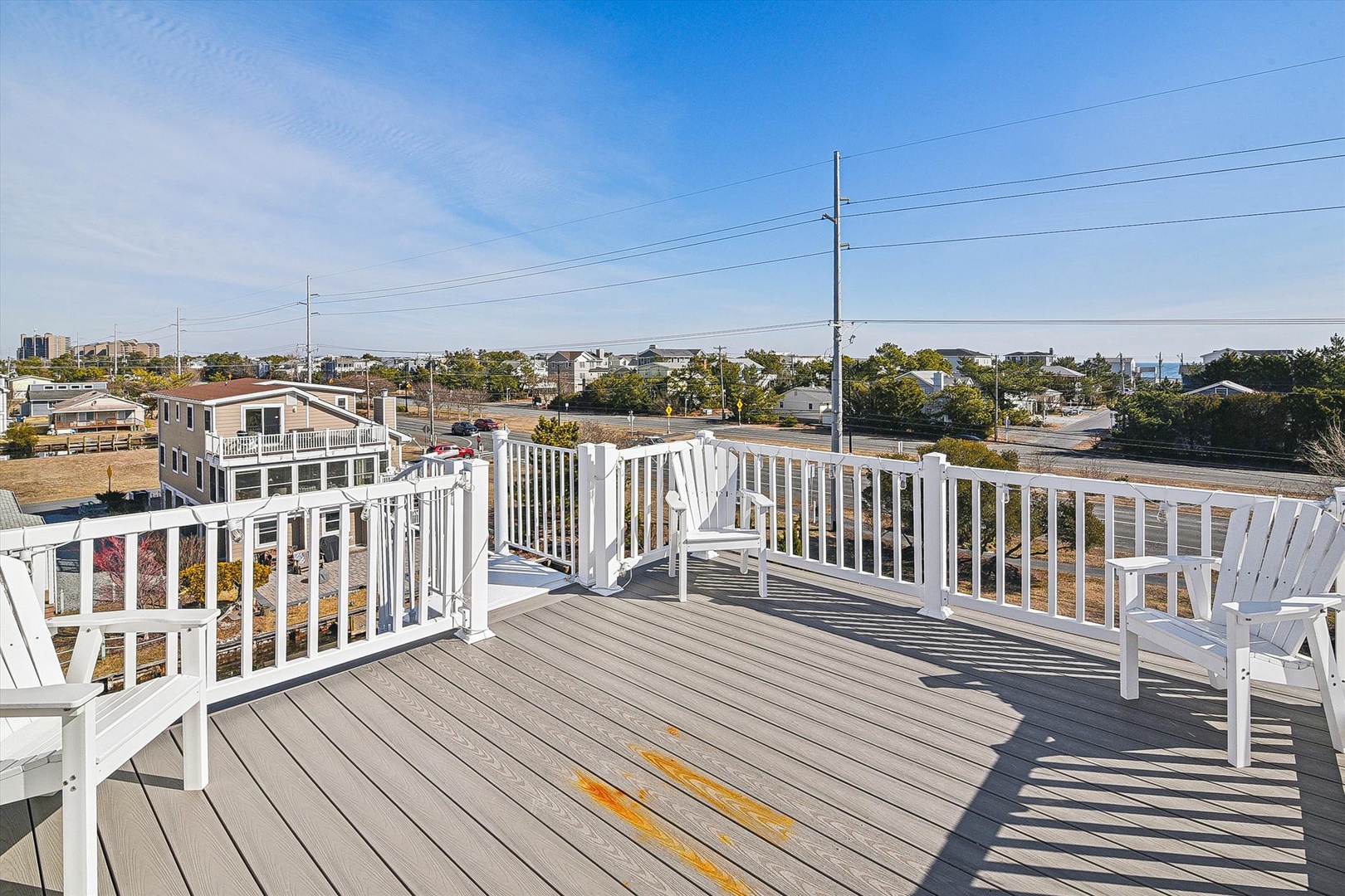 A spacious rooftop deck with white railings, Adirondack chairs, and coastal neighborhood views offers an elevated outdoor retreat during your stay.