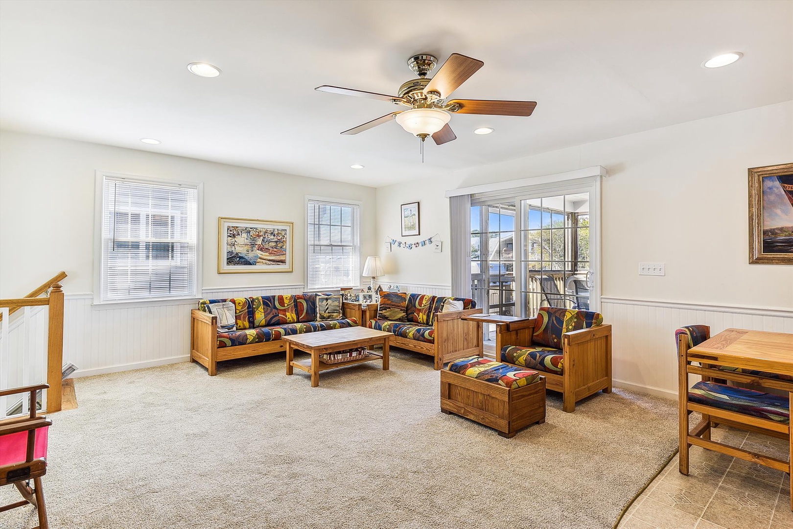 Bright and welcoming living room where you can unwind on comfy sofas, enjoy natural light streaming through balcony doors, and relax under the cooling ceiling fan after your day of adventure.