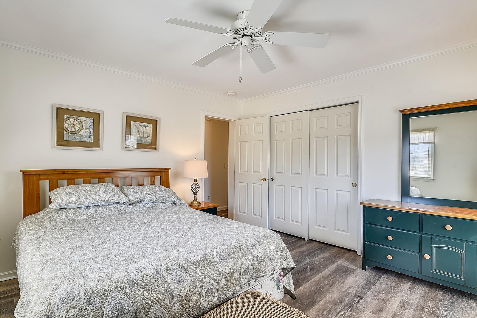 Your comfortable bedroom awaits with a cozy bed, gentle ceiling fan, and plenty of storage in the closet and dresser for a restful stay.