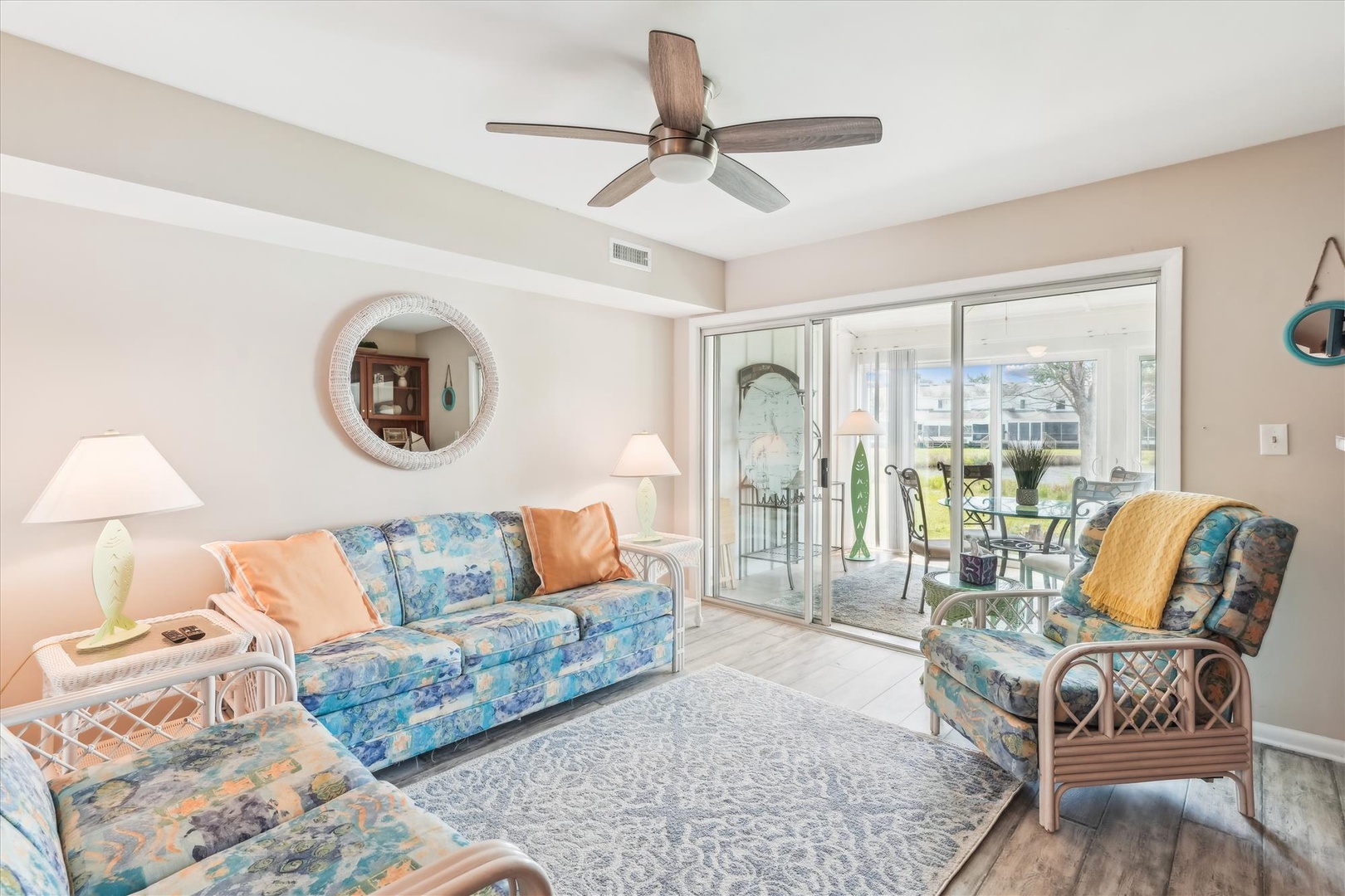 Unwind in your bright, beachy living room where colorful coastal furnishings and a gentle ceiling fan create perfect comfort for relaxing.