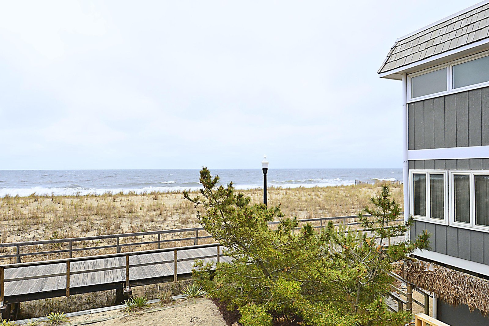Coastal property located steps from sandy shores with direct beach access via wooden walkway, offering serene ocean views in a tranquil beachfront setting.