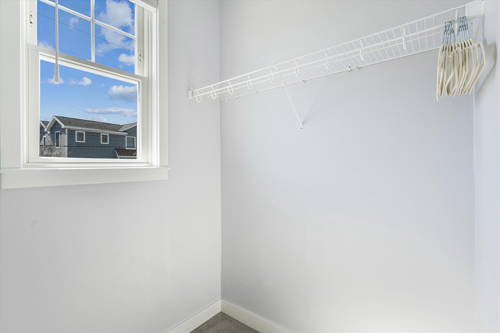 Bright closet with built-in wire shelving and hangers, offering plenty of space for your wardrobe—and a lovely window view to brighten your mornings.