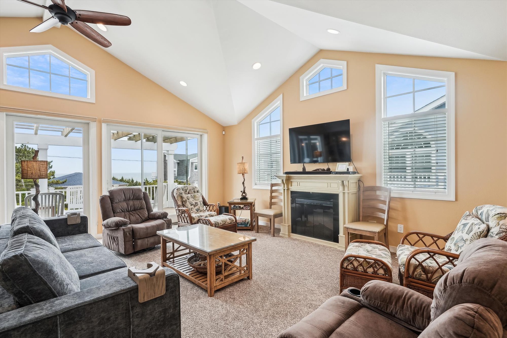 Settle into this spacious living room where vaulted ceilings and abundant natural light create an airy retreat. Sink into plush seating by the fireplace, with stunning water views beyond.