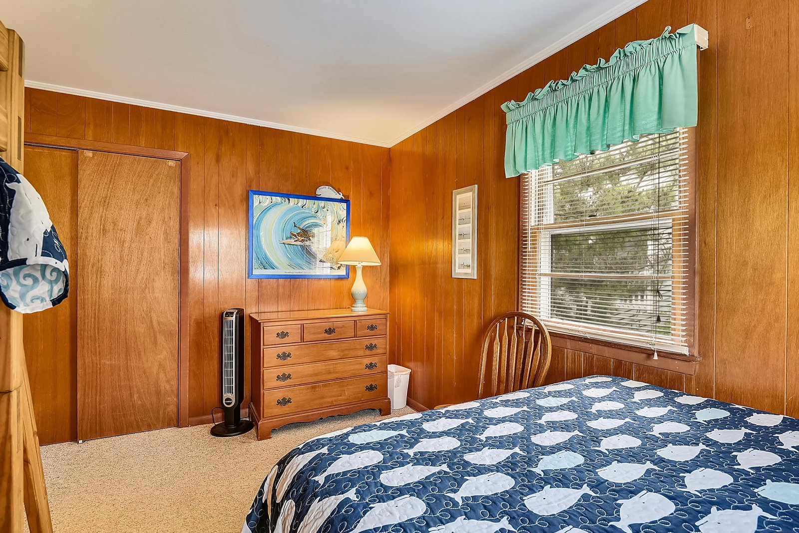 Unwind in your cozy bedroom with warm wood paneling and nautical touches, where gentle breezes drift through the window and soft bedding invites restful sleep.
