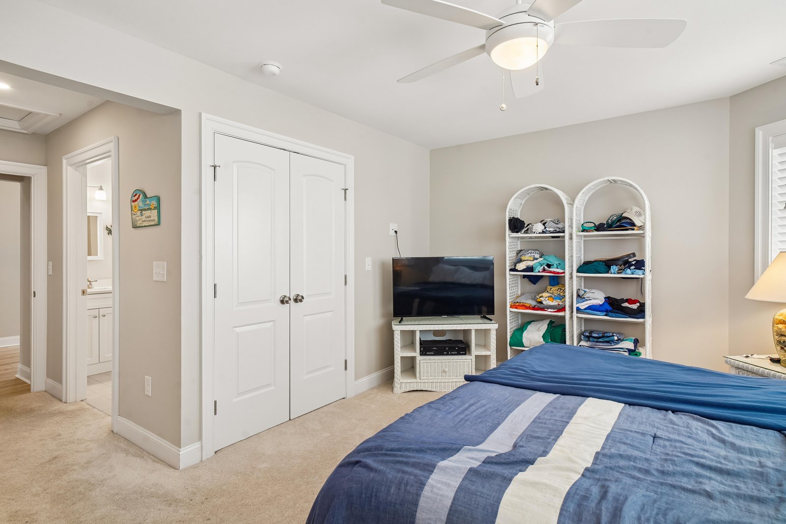 Your comfortable bedroom features a ceiling fan, coastal decor touches, and a dedicated TV area with plenty of storage to keep your belongings neatly organized throughout your stay.