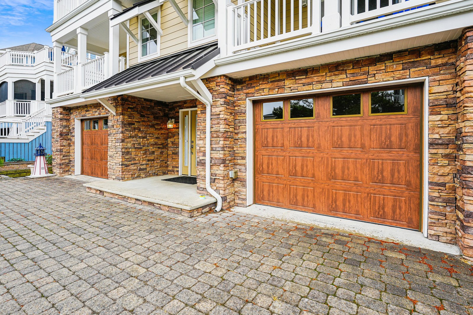 A charming coastal property featuring stone accents, warm wood garage doors, and classic white balconies. Convenient parking with secure covered entry and nearby beach access.