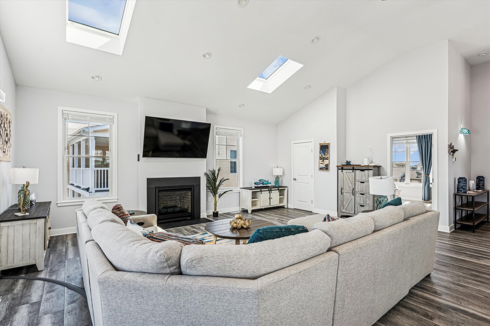 Relax in your bright living room with soaring skylights, cozy fireplace, and plush sectional seating perfect for unwinding after beach adventures.