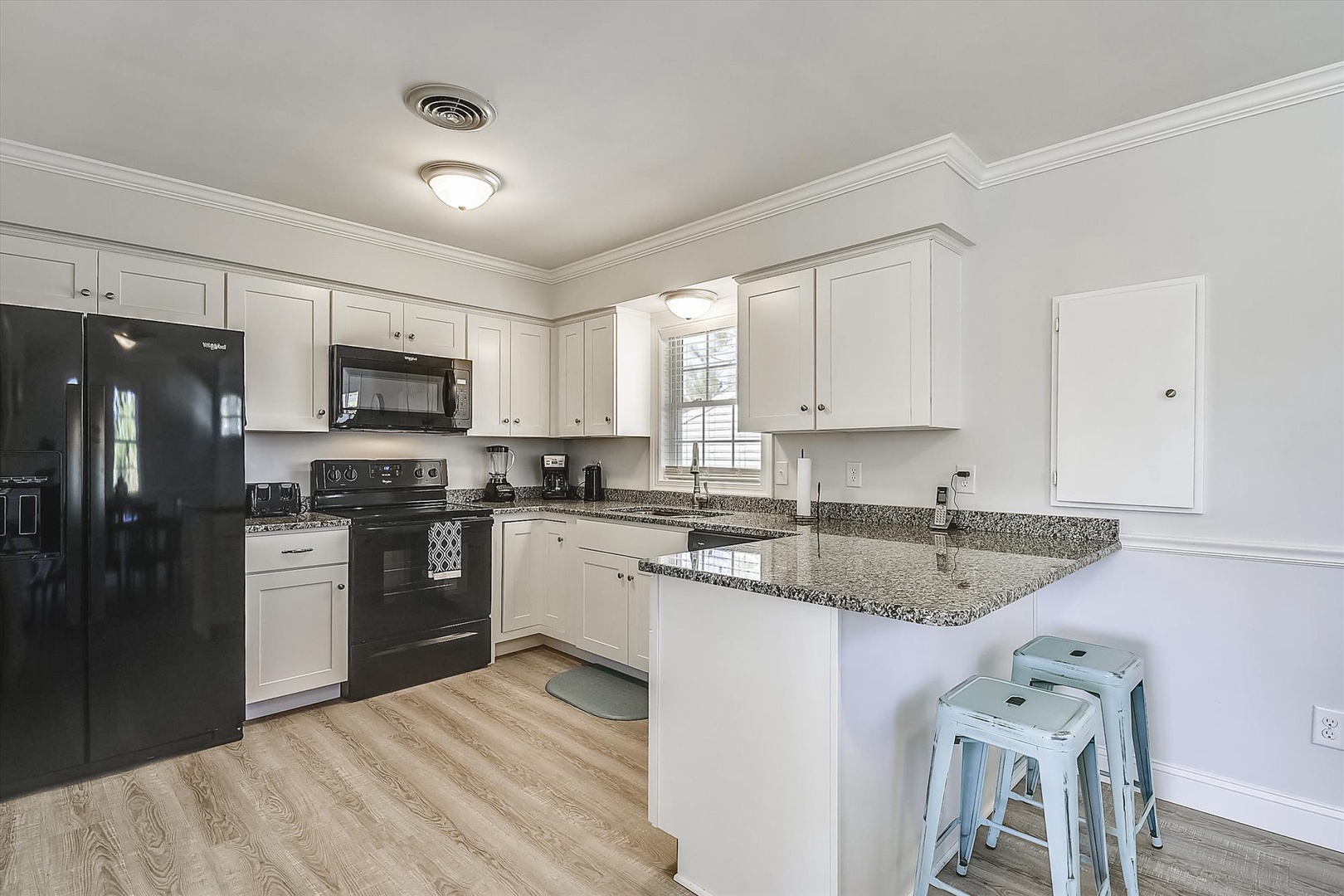 You'll love preparing meals in this bright, fully equipped kitchen with modern appliances, granite counters, and a cozy breakfast bar perfect for morning coffee.