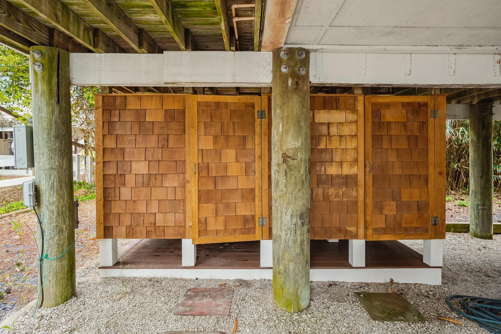 Outdoor storage with beautifully crafted wooden doors, tucked beneath the covered area—practical space for keeping beach gear and essentials organized.