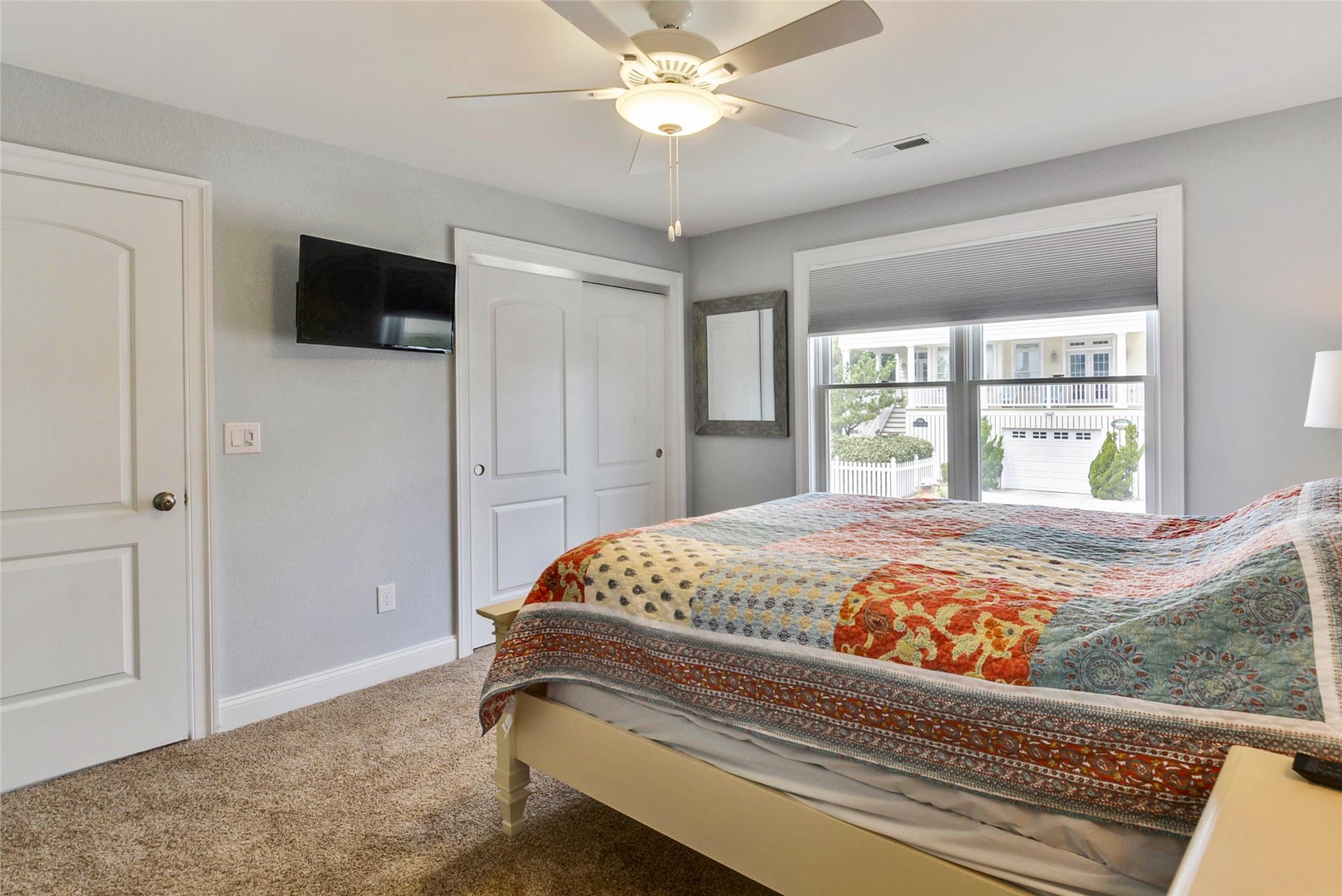 Settle into your bright, welcoming bedroom with soft carpeting underfoot, a cozy bed dressed in vibrant linens, and peaceful neighborhood views framing your stay.