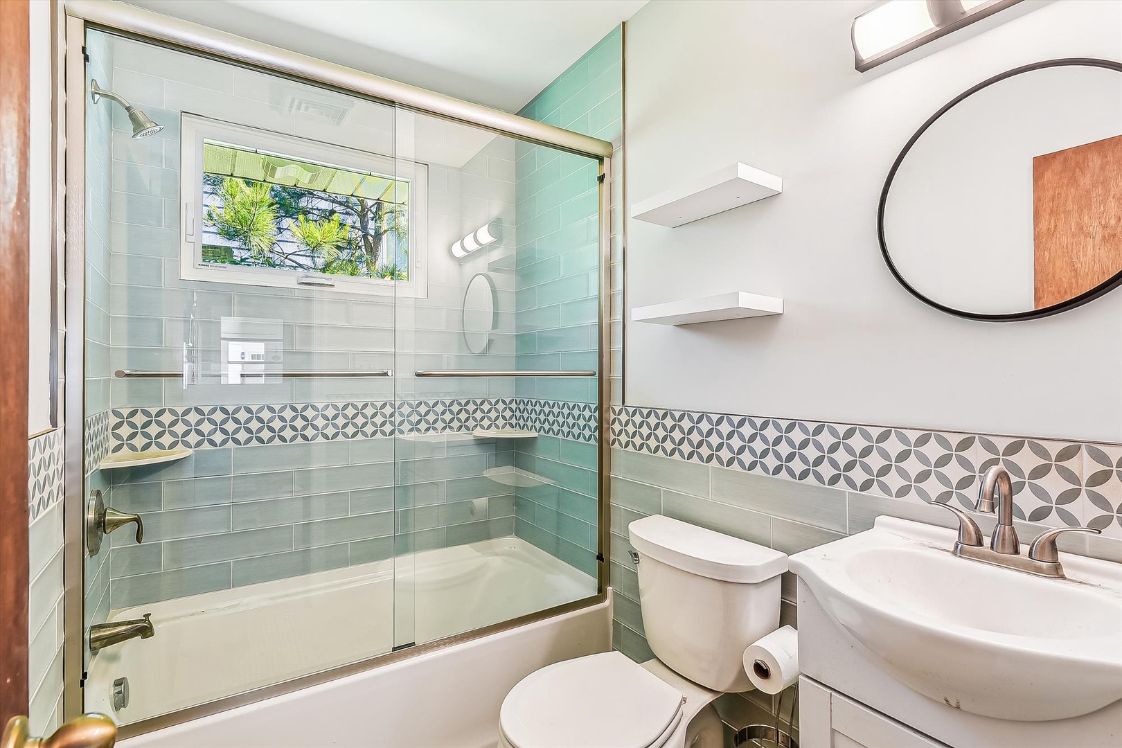 Fresh and inviting, this beautifully tiled bathroom blends calming aqua hues with geometric accents, offering you a serene space to unwind and refresh.