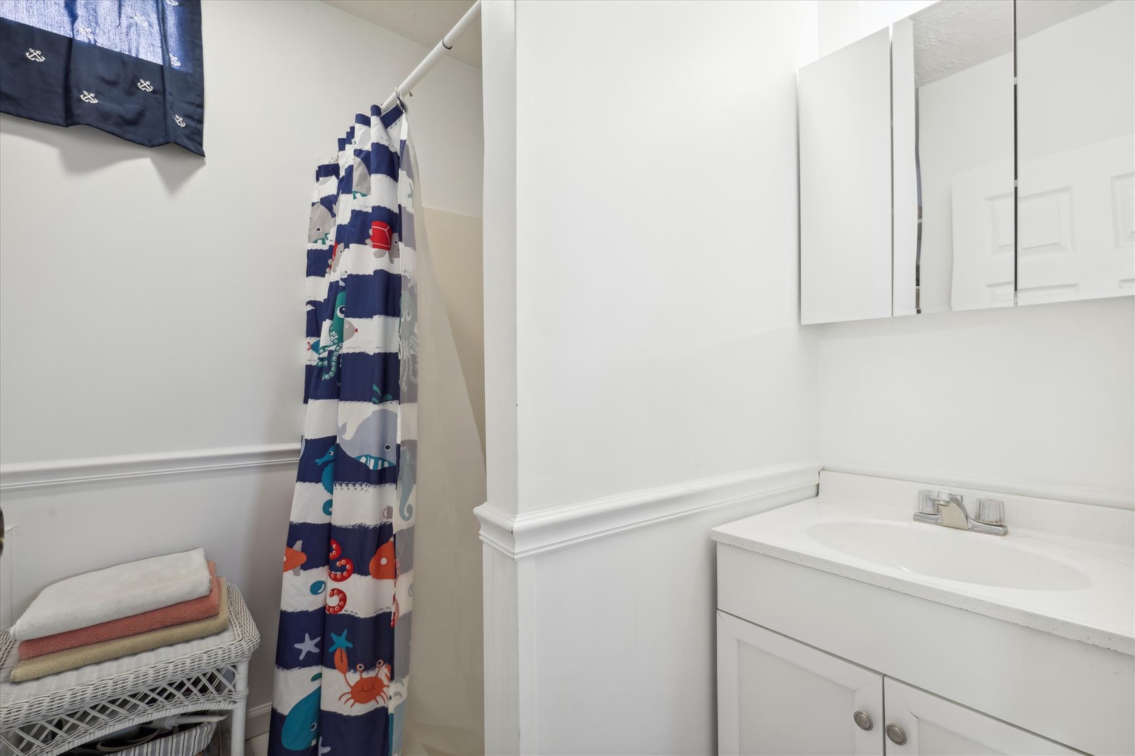 Your spotless bathroom offers fresh towels, a playful nautical shower curtain, and plenty of cabinet space to make you feel right at home.